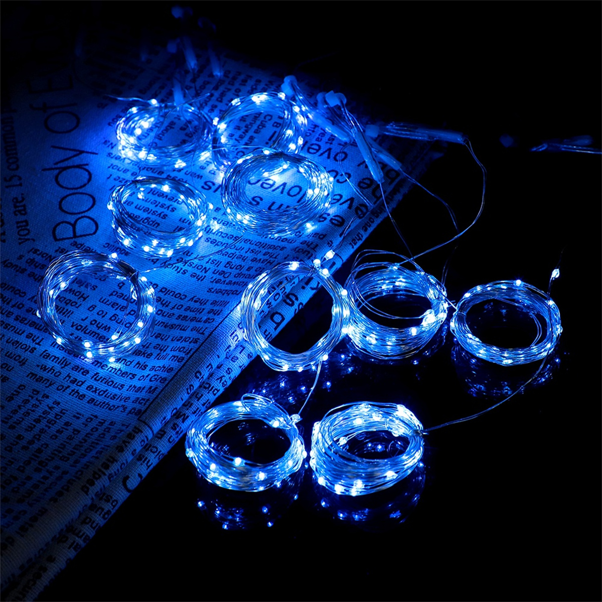 Blaue LED-Lichterketten auf einer reflektierenden Oberfläche mit Zeitungshintergrund.