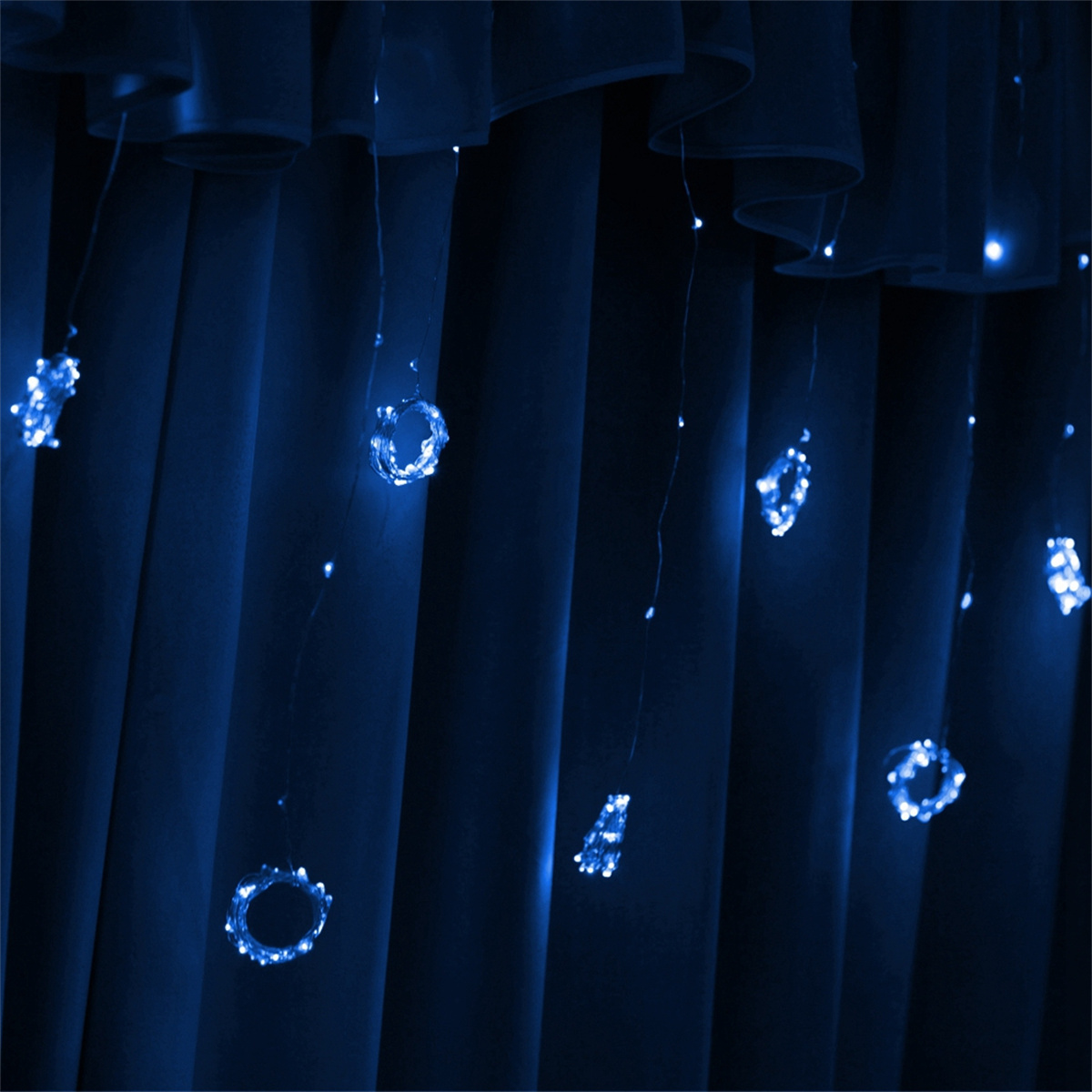 Blaue Lichterketten hängen vor einem dunkelblauen Vorhang. Die Lichter haben ein kreisförmiges Design.