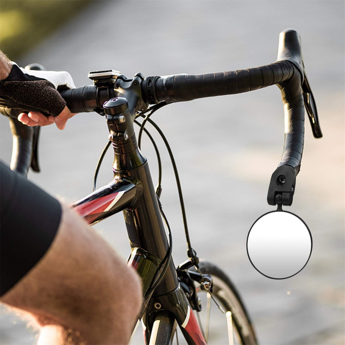 Fahrradlenker mit einem daran befestigten Spiegel. Der Arm einer Person ist sichtbar.