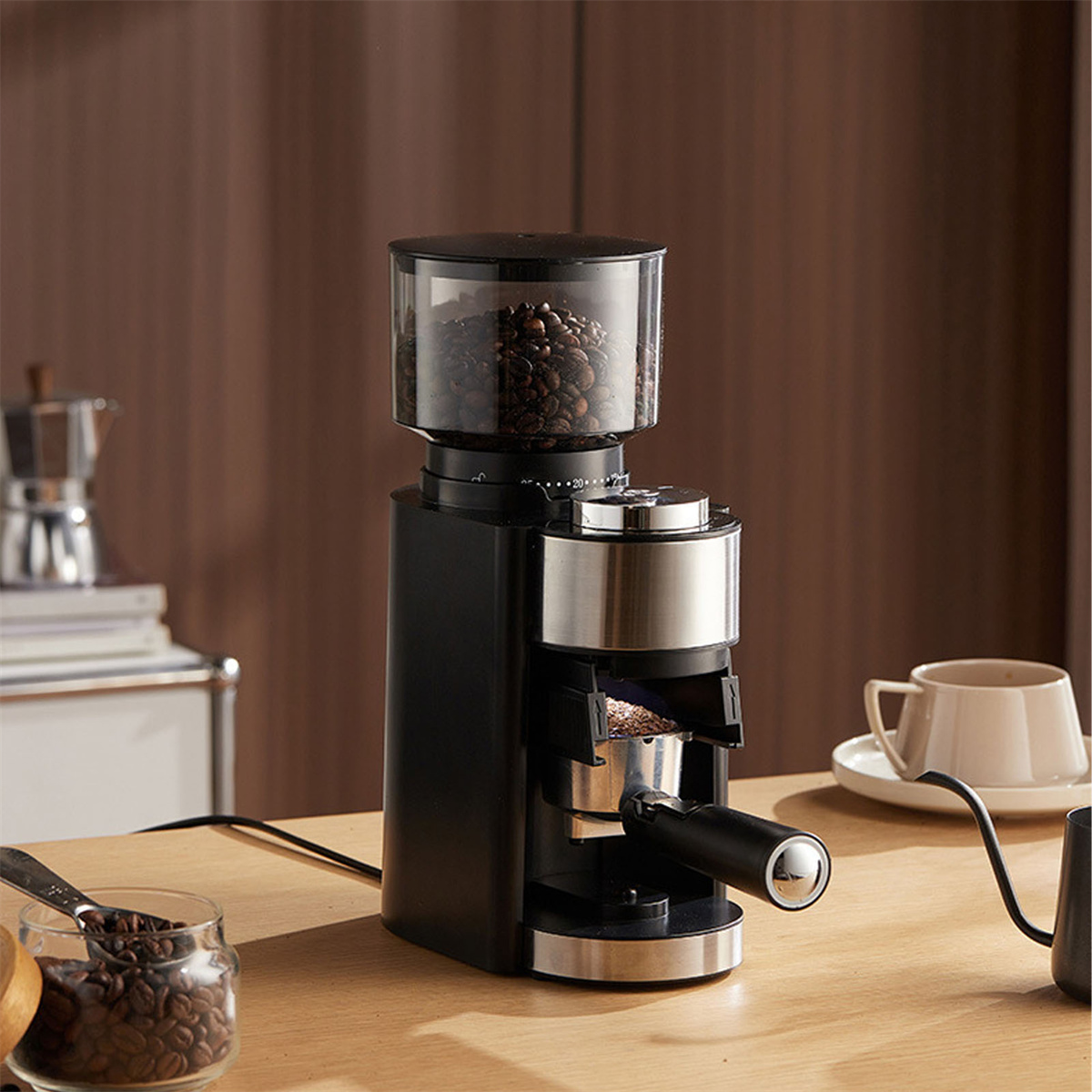 Schwarze und silberne Kaffeemühle mit Bohnen oben und Mahlgut im Siebträger.
