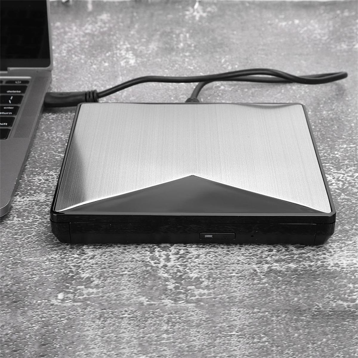 Eine schwarze und silberne externe Festplatte neben einem Laptop.