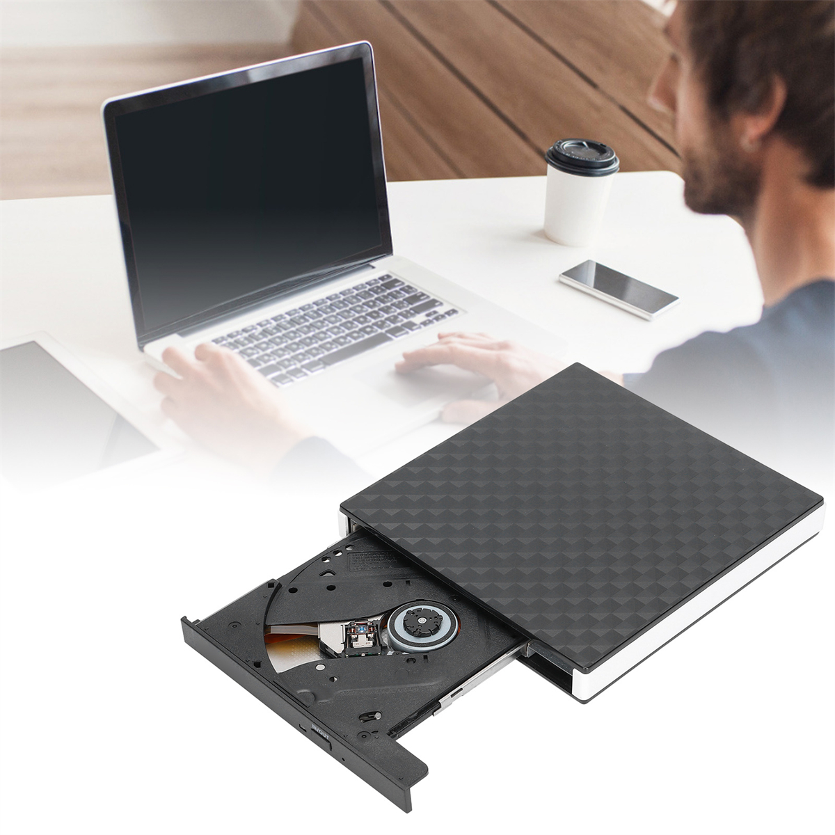Eine Person arbeitet an einem Laptop mit einem DVD-Laufwerk daneben. Das Laufwerk ist geöffnet.