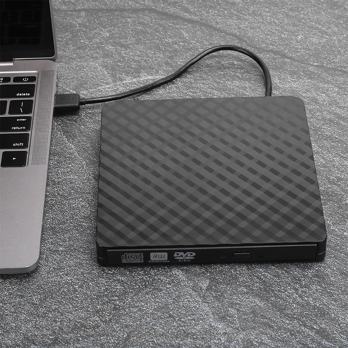 Externes schwarzes DVD-Laufwerk, an einen Laptop angeschlossen. Es liegt auf einer Textur.
