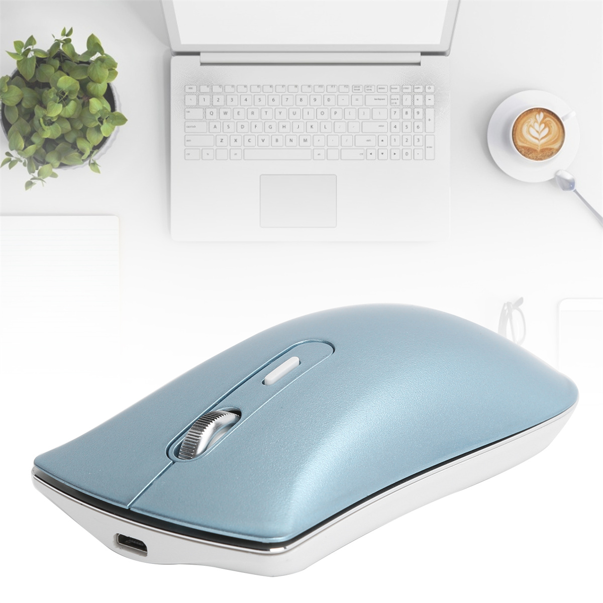 Blaue kabellose Maus, ein weißer Laptop und eine Tasse Kaffee auf einem weißen Tisch.