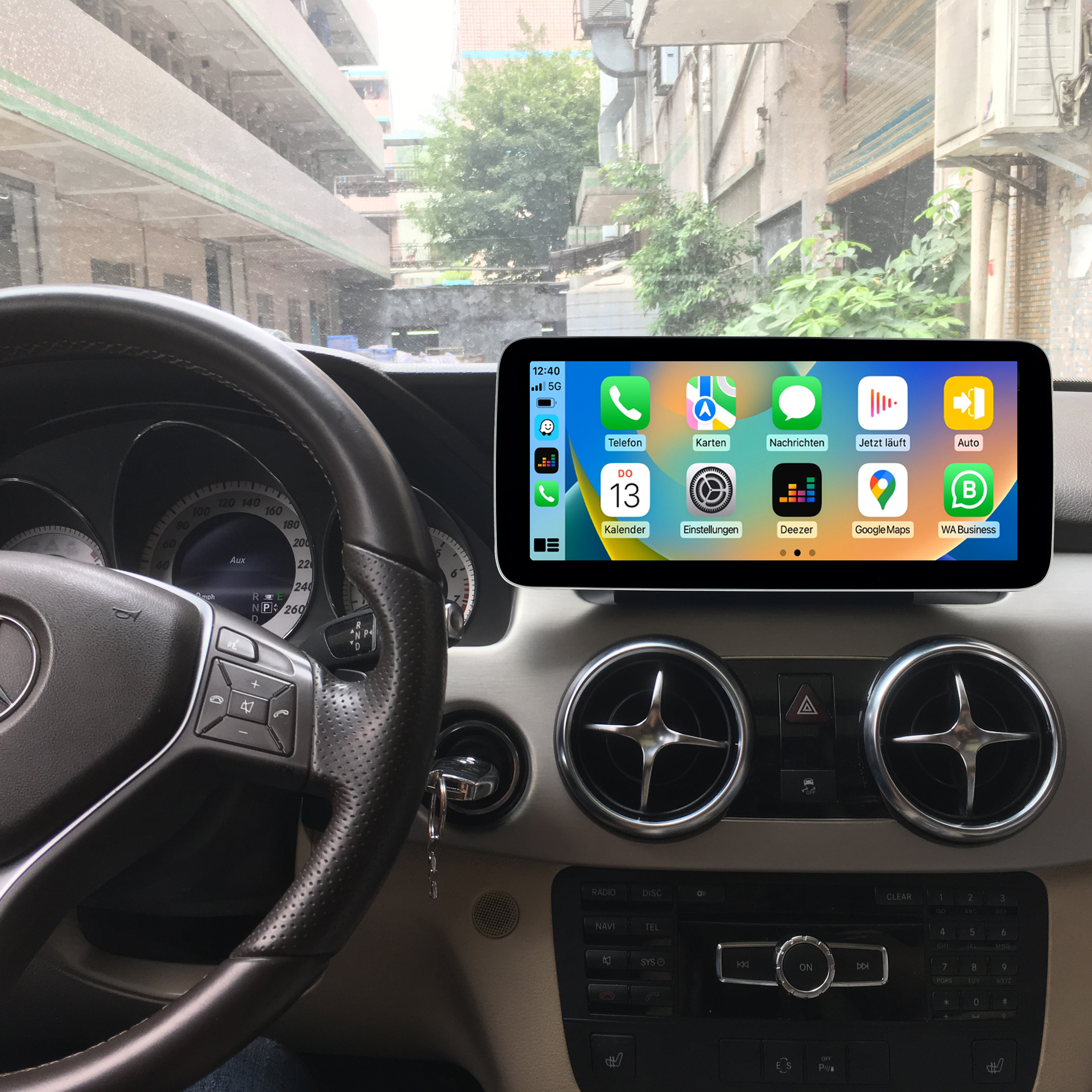 Autoinnenraum mit einem Telefon, das eine Navigations-App und eine Stadtansicht zeigt.