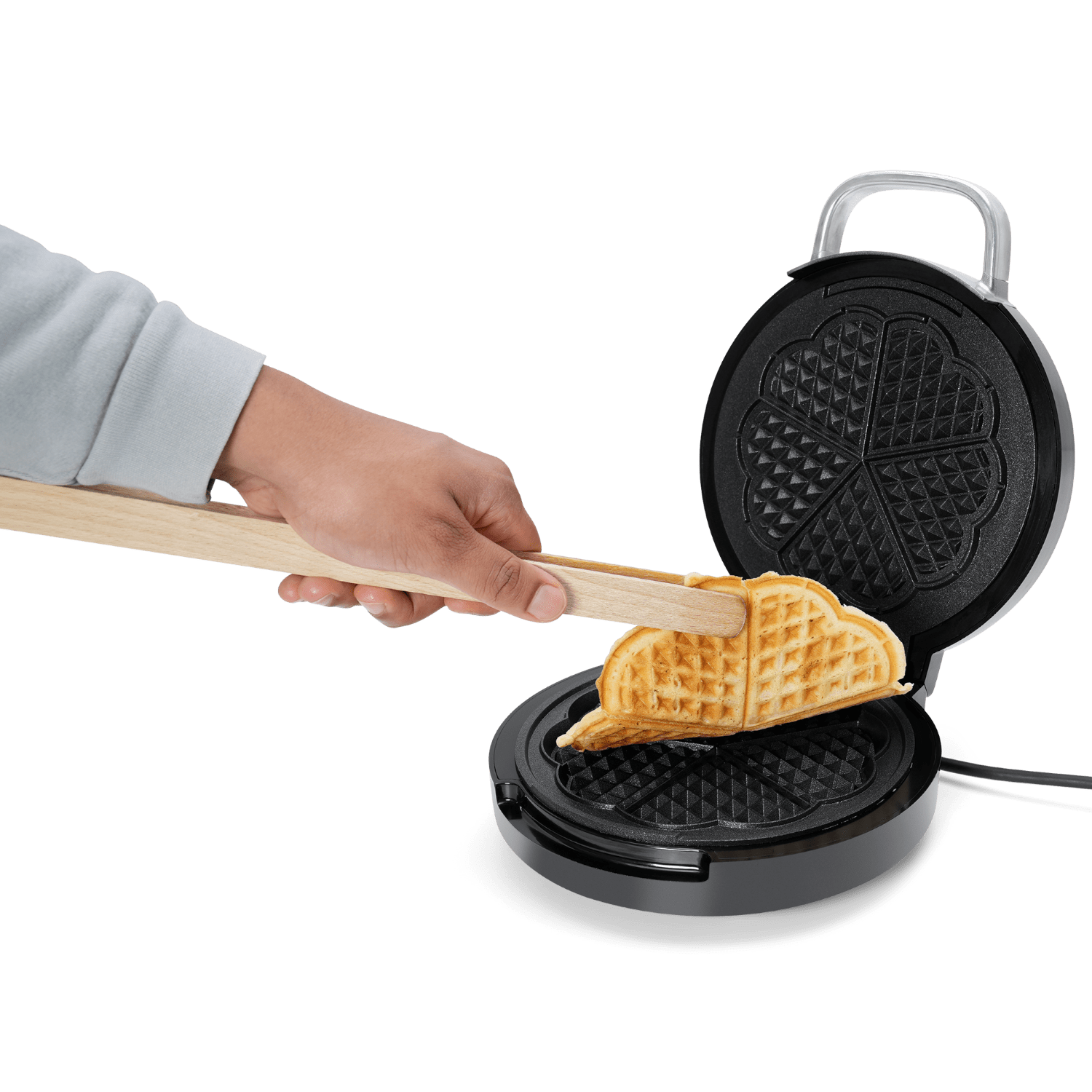 Eine Person, die eine Zange benutzt, um einen Waffel aus einem Waffeleisen zu nehmen. Schwarzer Hintergrund.
