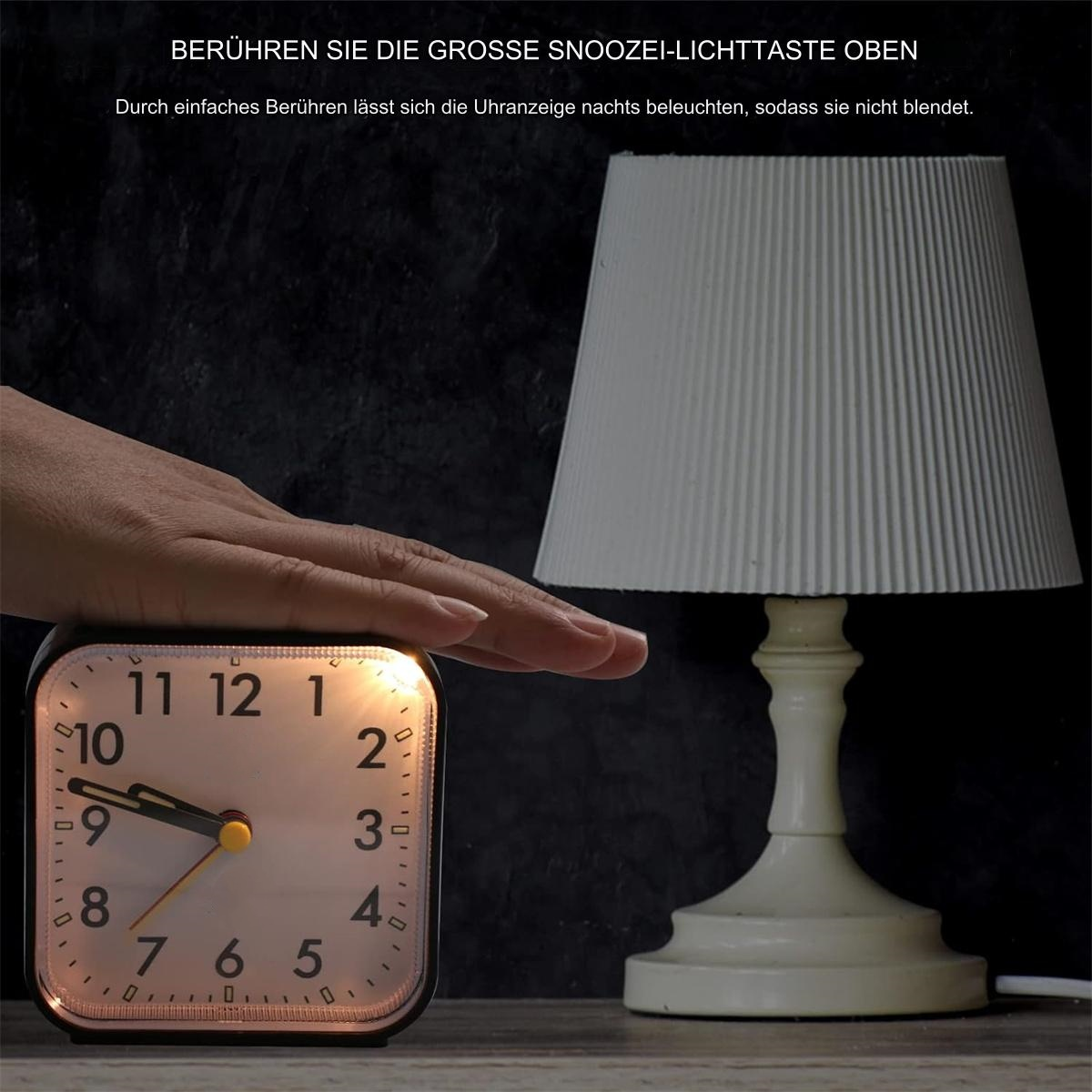 Eine Hand berührt einen beleuchteten Wecker neben einer Lampe.