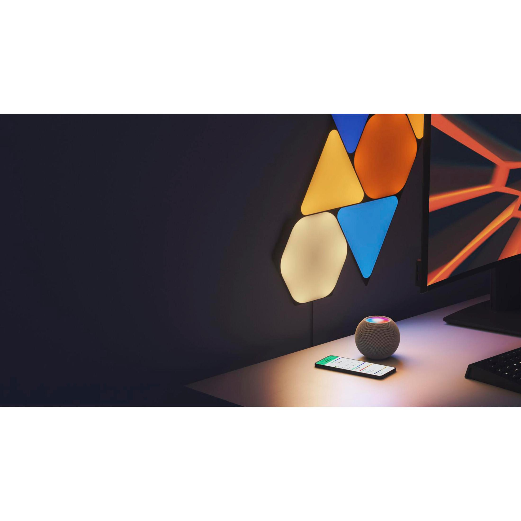 Una stanza con una scrivania, uno smart speaker, uno smartphone e luci esagonali sulla parete. Le luci sono multicolore.