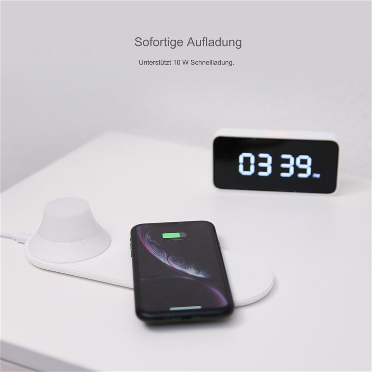 Ein weißes kabelloses Ladegerät mit einem ladenden Telefon und einem digitalen Wecker.