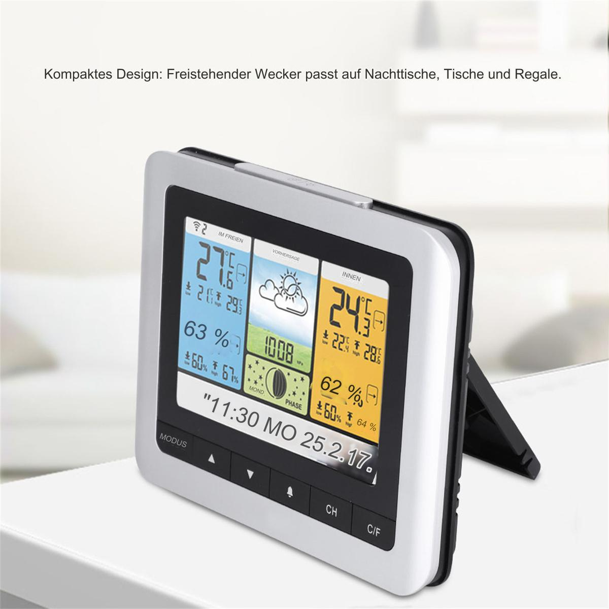 Eine digitale Wetterstation zeigt Temperatur, Luftfeuchtigkeit und Wetterbedingungen auf einer weißen Oberfläche an.