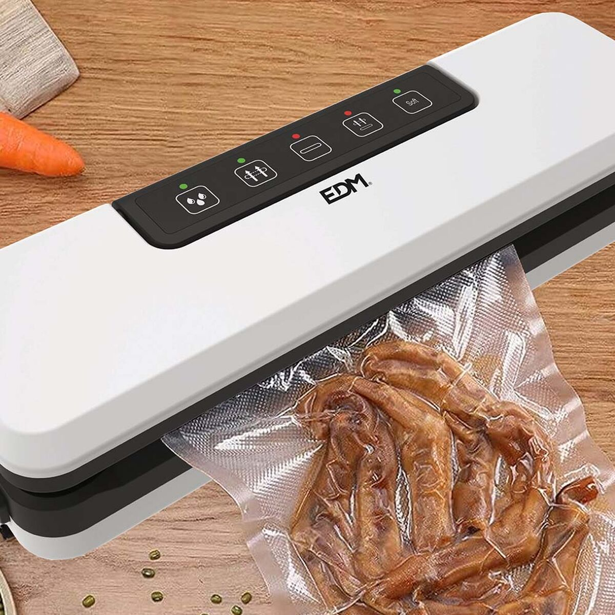 Biało-czarna zgrzewarka próżniowa z workiem z jedzeniem. Z boku marchewka.