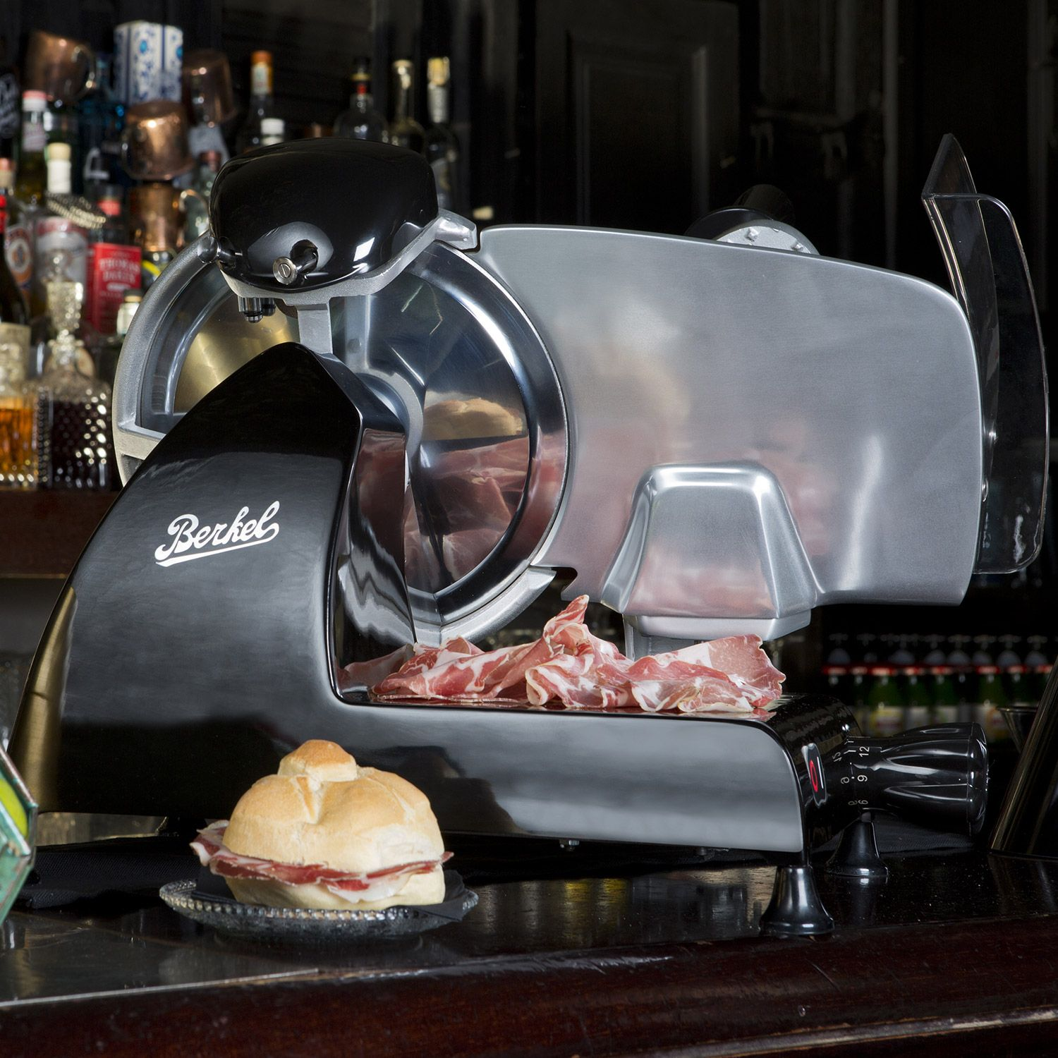 Eine Fleischschneidemaschine mit einem Sandwich und geschnittenem Fleisch auf einer Bar.
