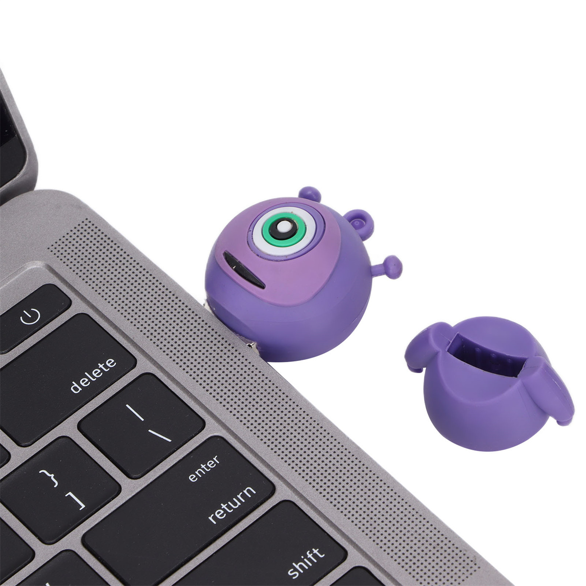 Lila Monster-USB-Stick neben einem Laptop, mit separater Kappe.