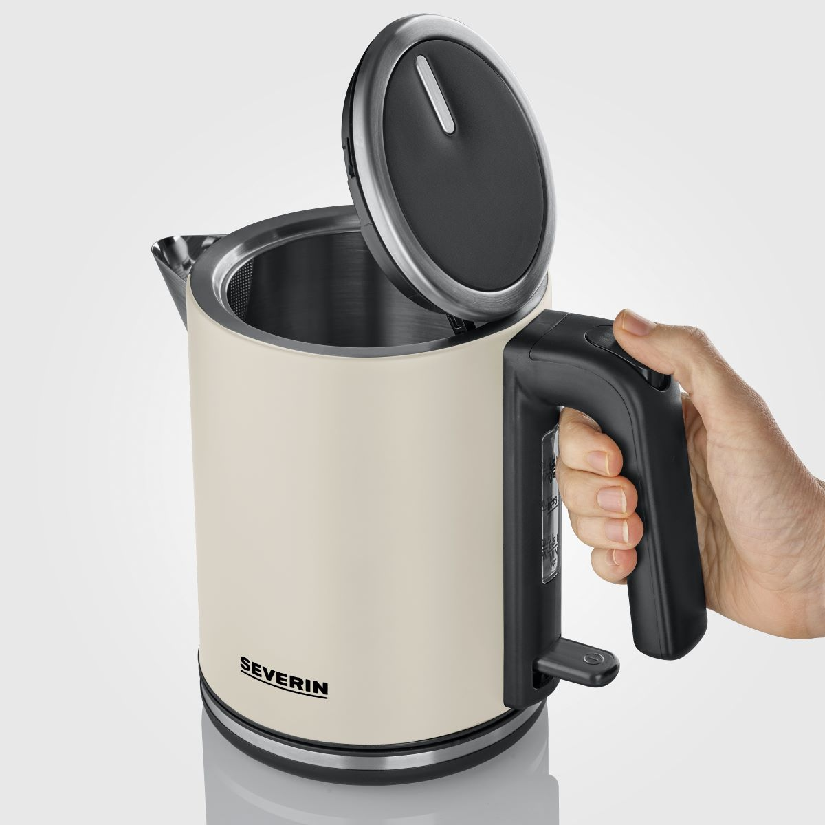 Een crèmekleurige elektrische waterkoker met open deksel, zwarte handgreep en een hand.