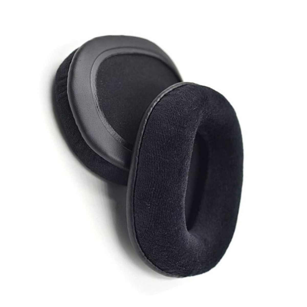 Dwie czarne wkładki do uszu, do słuchawek, leżące na białej powierzchni.