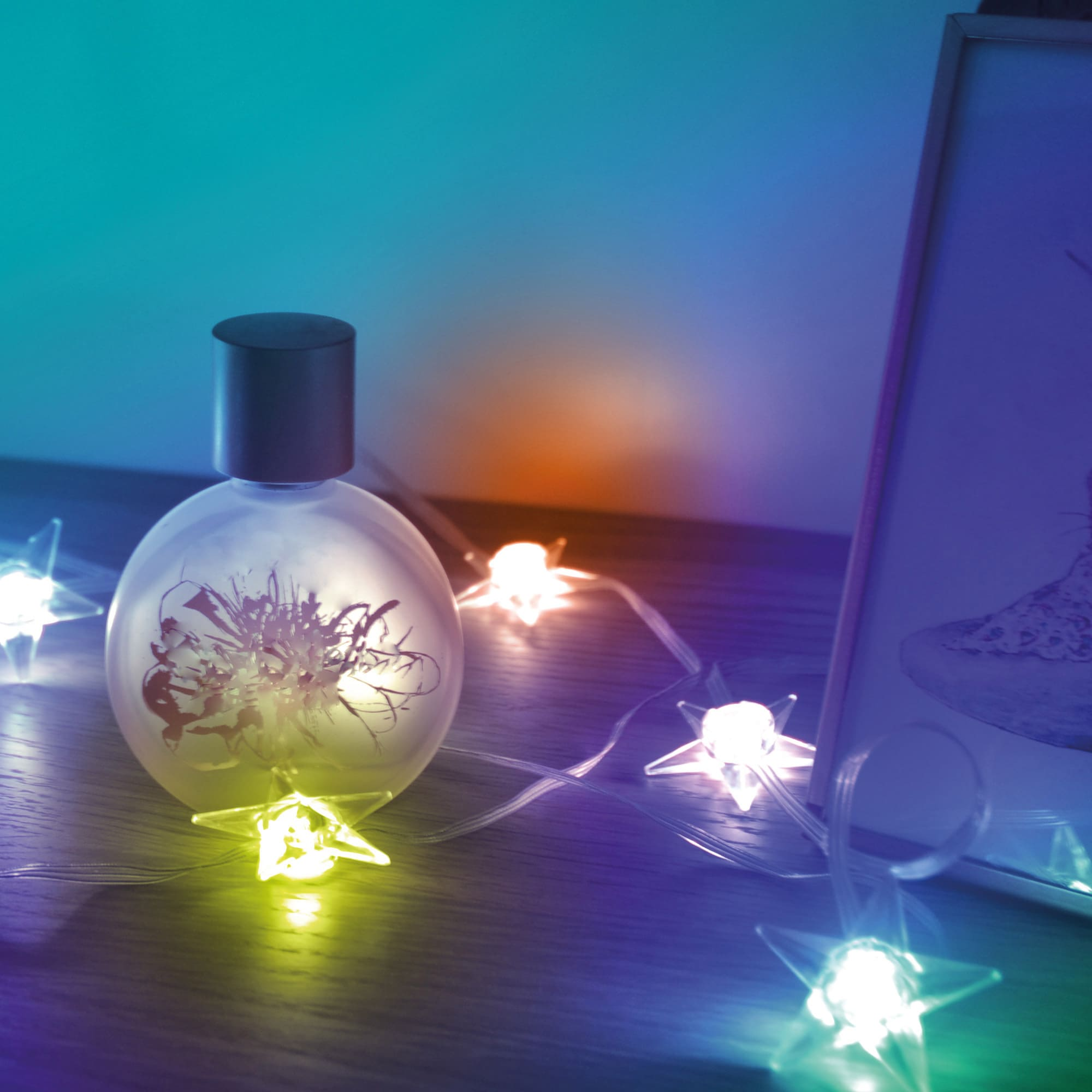 Butelka perfum z lampkami i ramką na drewnianej powierzchni.