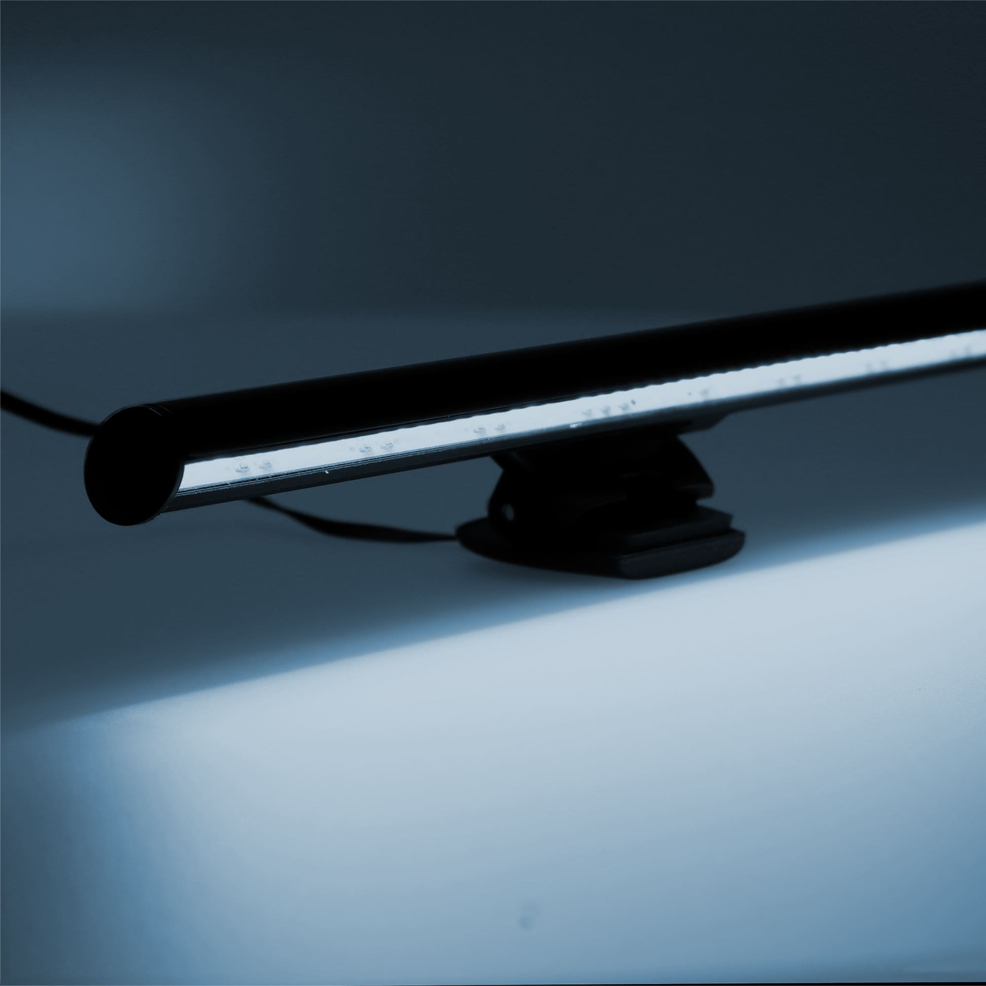 Lámpara de escritorio cilíndrica negra con una barra de luz blanca brillante.