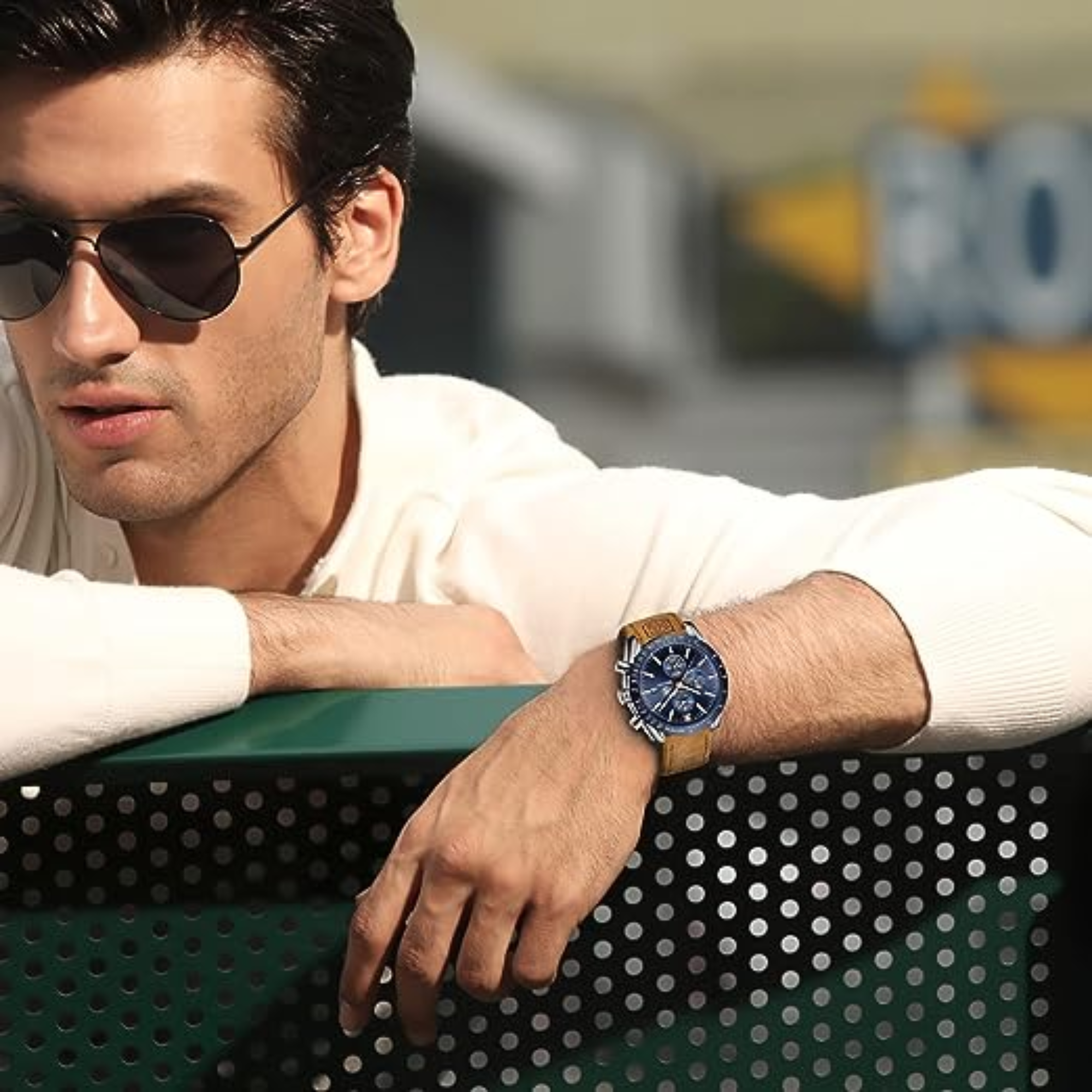 Hombre con gafas de sol y reloj. El fondo está borroso.