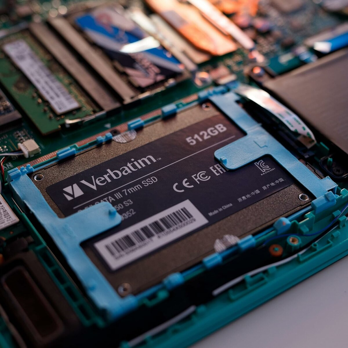 Dysk SSD Verbatim 512 GB zainstalowany w laptopie. Niebieska taśma go trzyma. Widoczne inne komponenty.