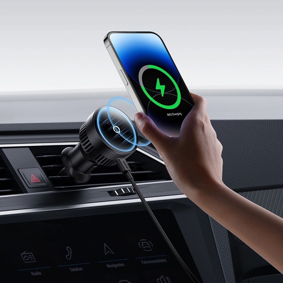 De hand van een persoon die een telefoon vasthoudt die oplaadt op een zwarte autolader. De telefoon toont een oplaadsymbool.
