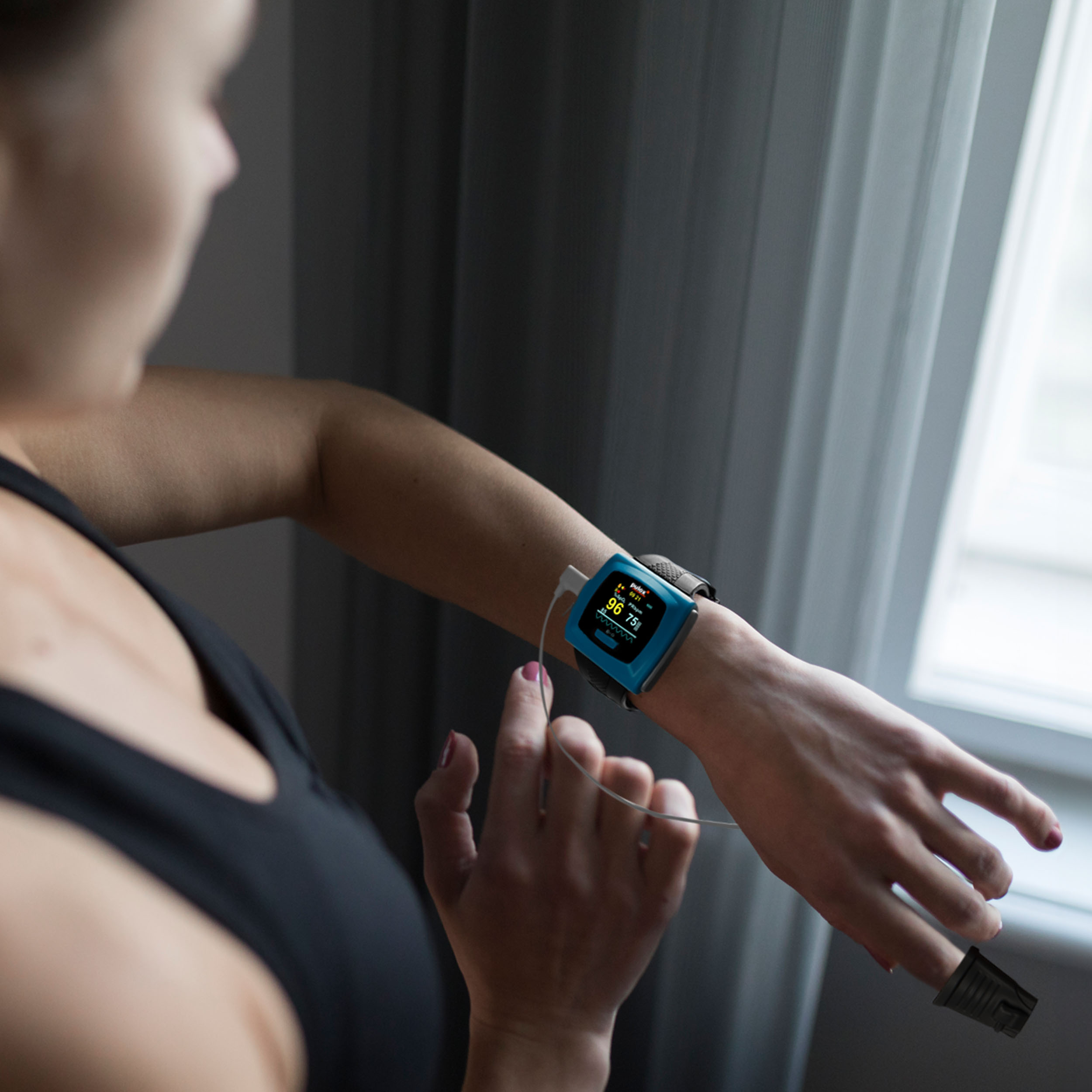 Eine Frau, die ein Handgelenkgerät trägt, das den Blutsauerstoffgehalt misst, mit einem Fingersensor.