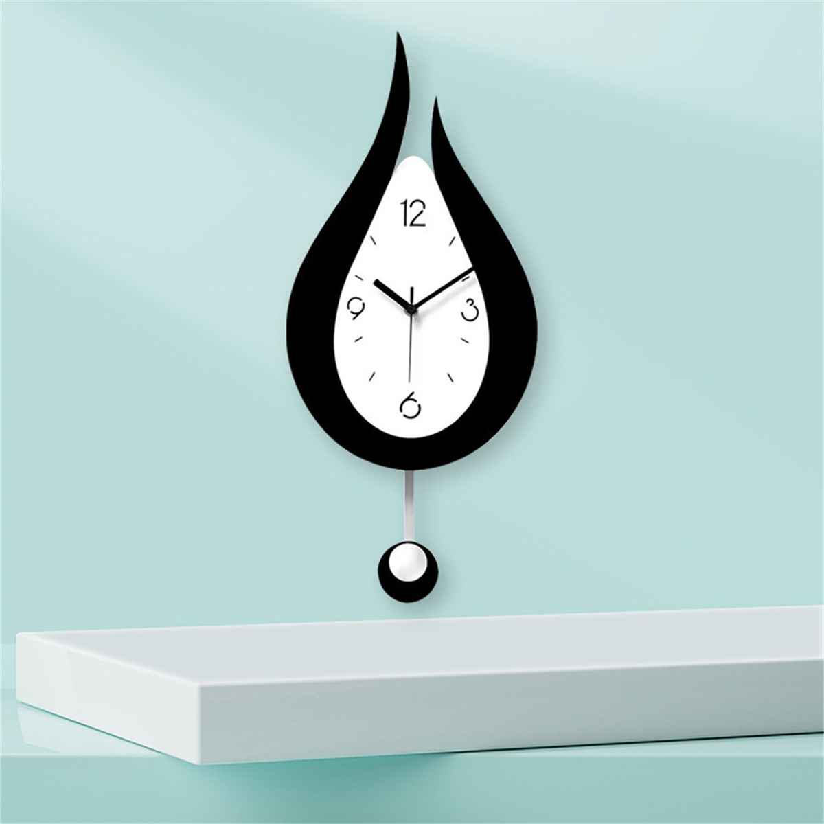Eine schwarz-weiße, tropfenförmige Uhr, die an einer hellblauen Wand hängt.
