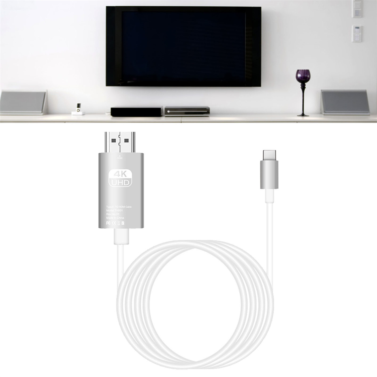Ein silbernes HDMI-Kabel ist an einen Monitor und einen USB-C-Anschluss angeschlossen. Ein Fernseher ist an der Wand montiert.