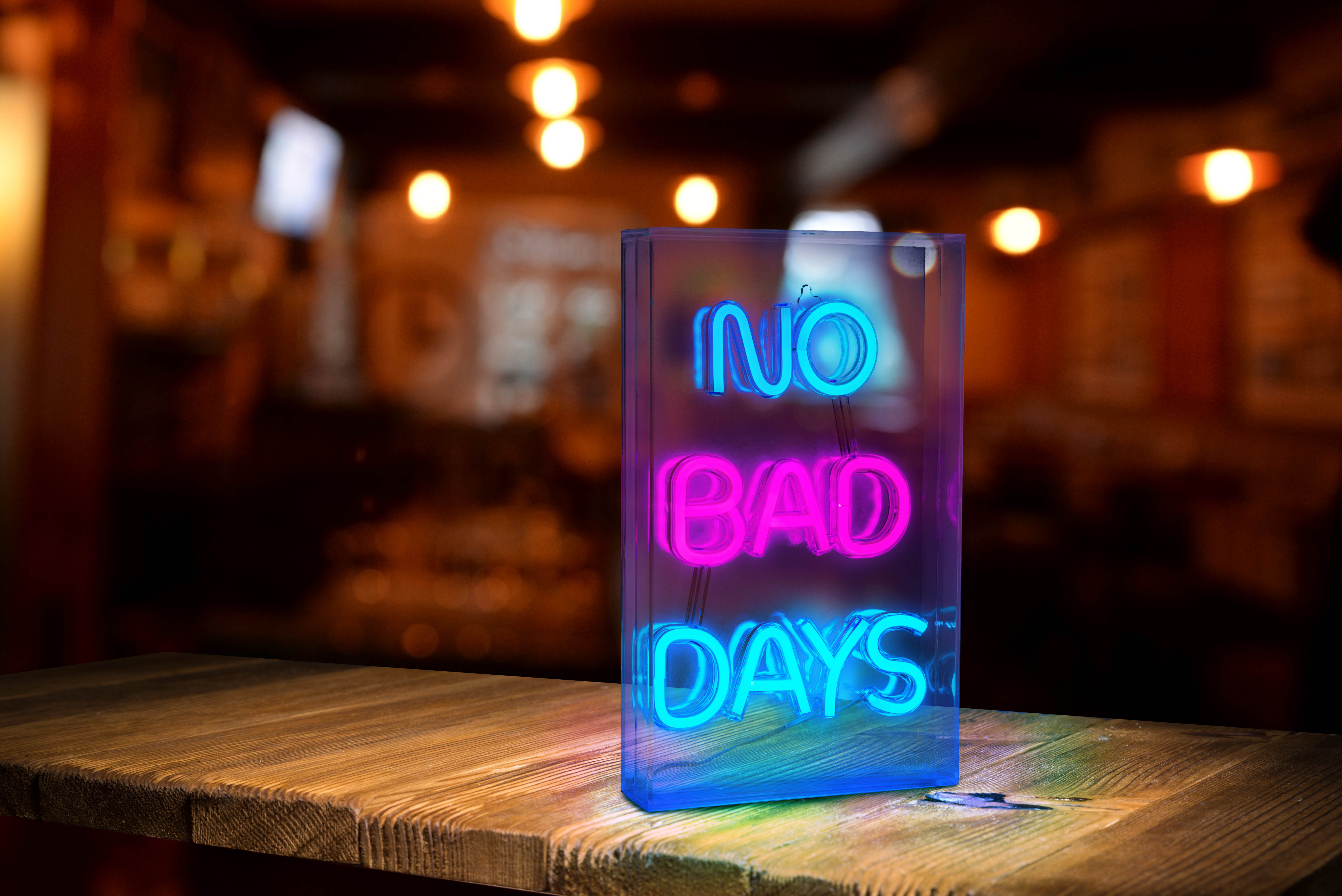 Neonschild auf einem Holztisch mit der Aufschrift „NO BAD DAYS“, verschwommener Hintergrund.