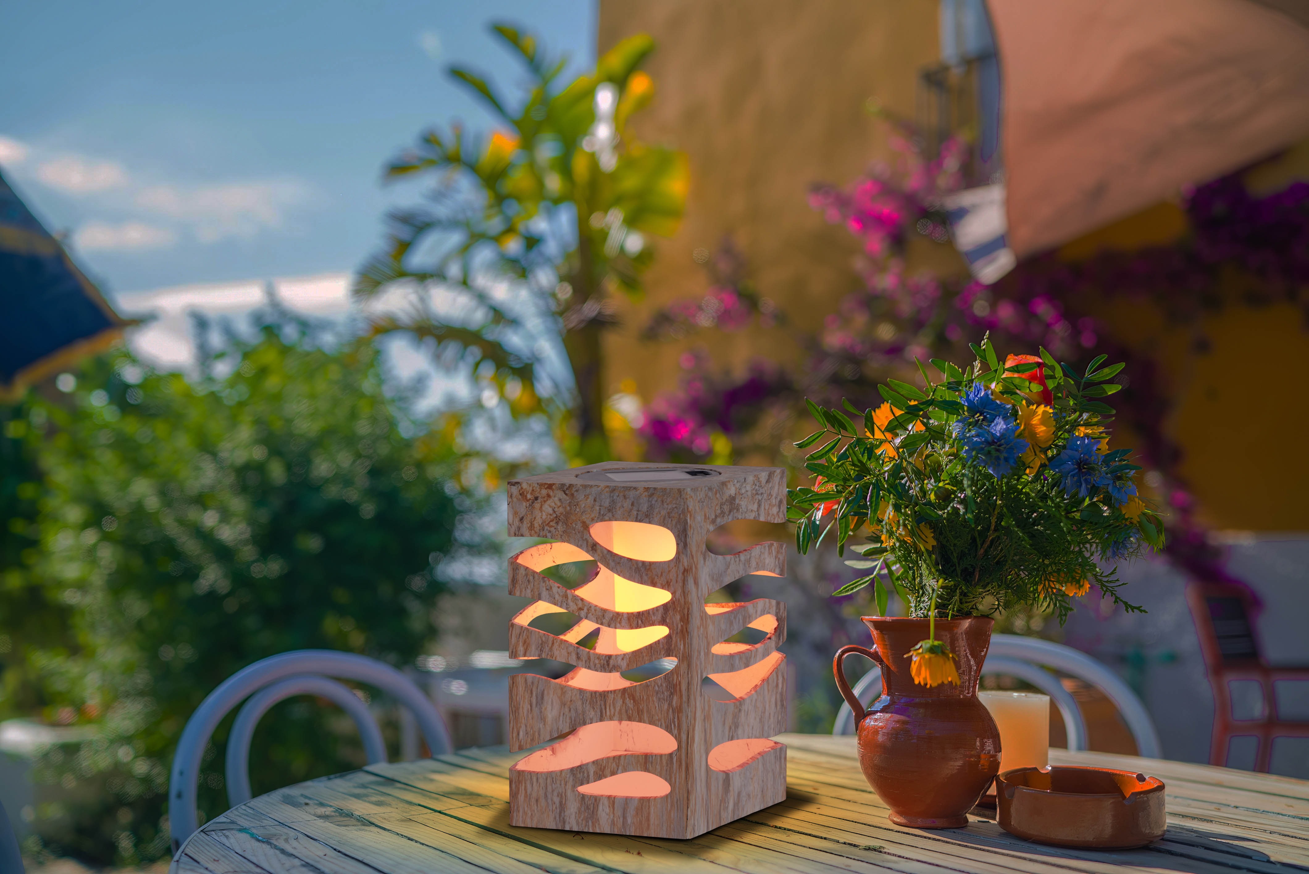 Holzlaterne auf einem Tisch mit Blumen und einer Kerze, Außenbereich mit Sonnenlicht.