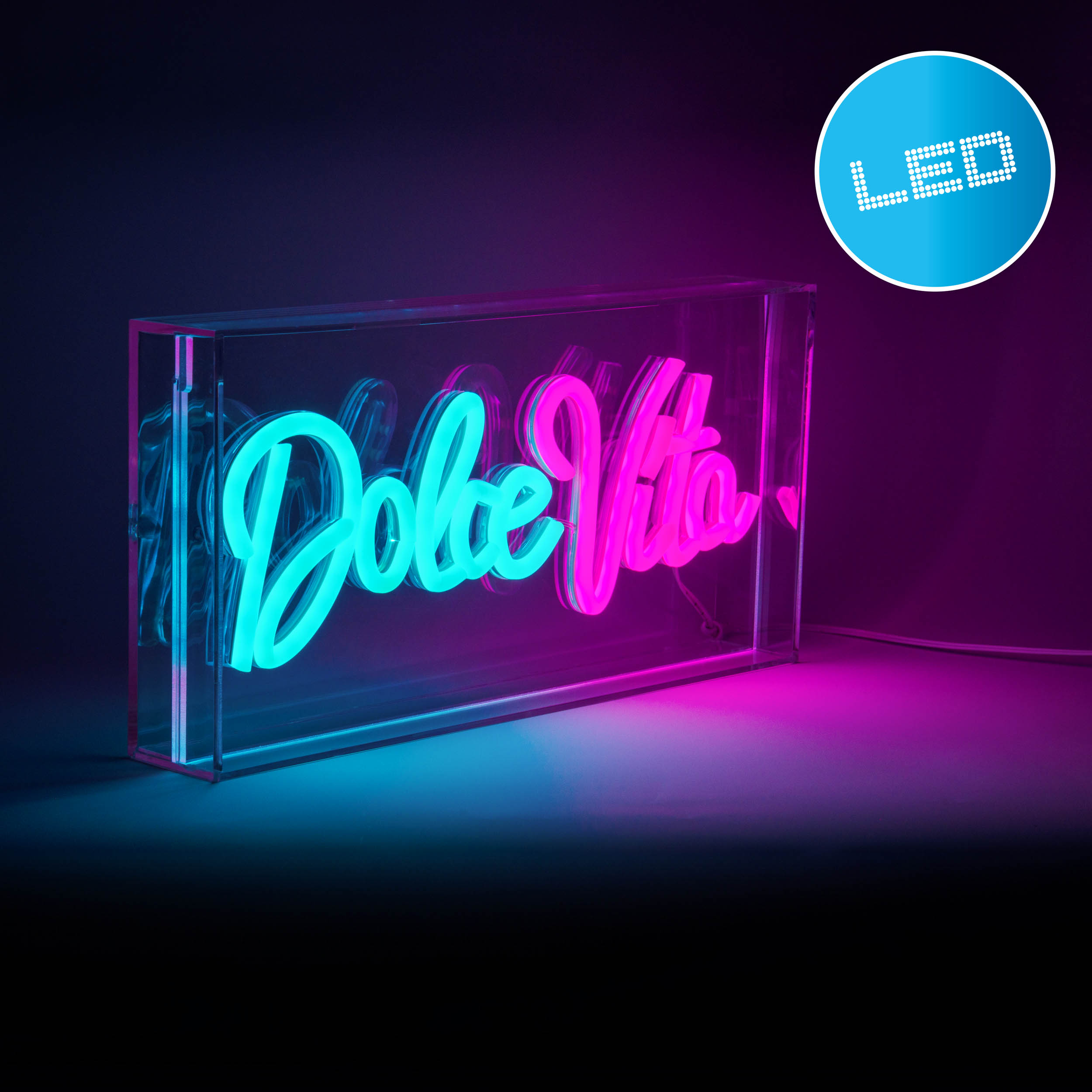 Ein Neonschild mit der Aufschrift 'Dolce Vita' in einer durchsichtigen Acrylbox, beleuchtet mit blauem und rosa Licht.