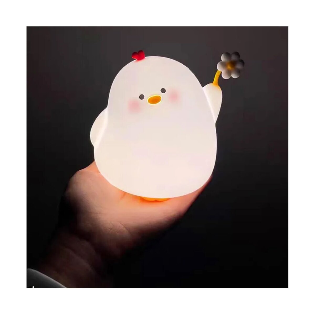 Ein weißes Küken-Nachtlicht, das von einer Hand gehalten wird. Das Küken hat eine Blume und gerötete Wangen.