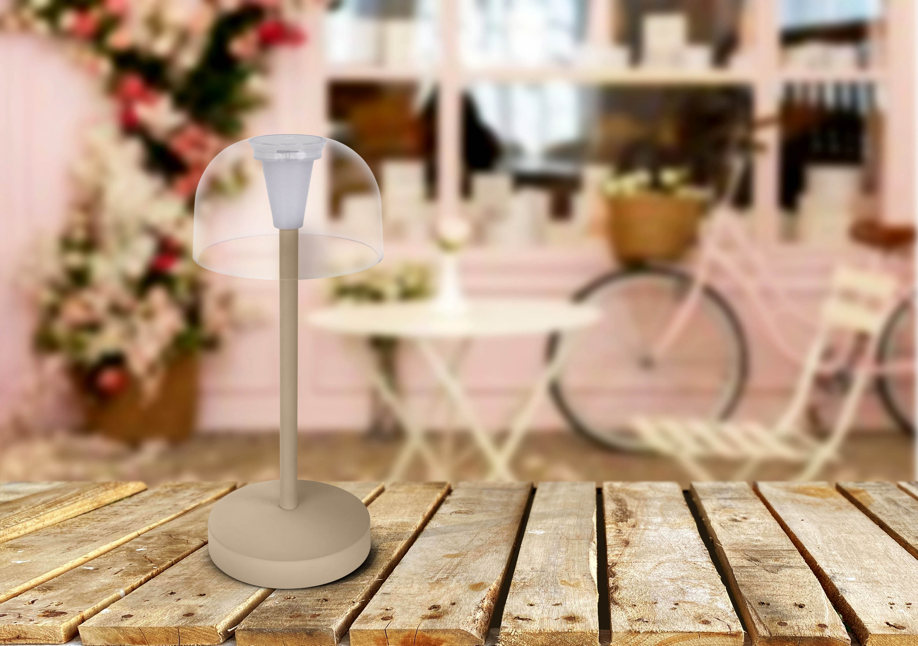 Eine Lampe mit hellbeigem Sockel, klarer Kuppel und hellem Hintergrund mit einem Fahrrad.