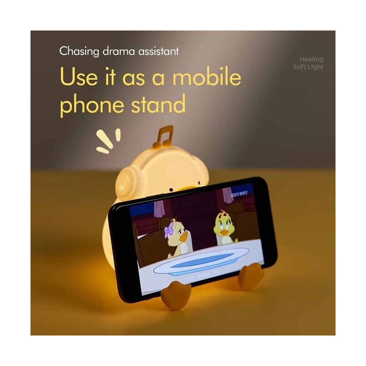 Eine gelbe Entenlampe, die ein Telefon mit Cartoons hält, mit sanftem Licht.