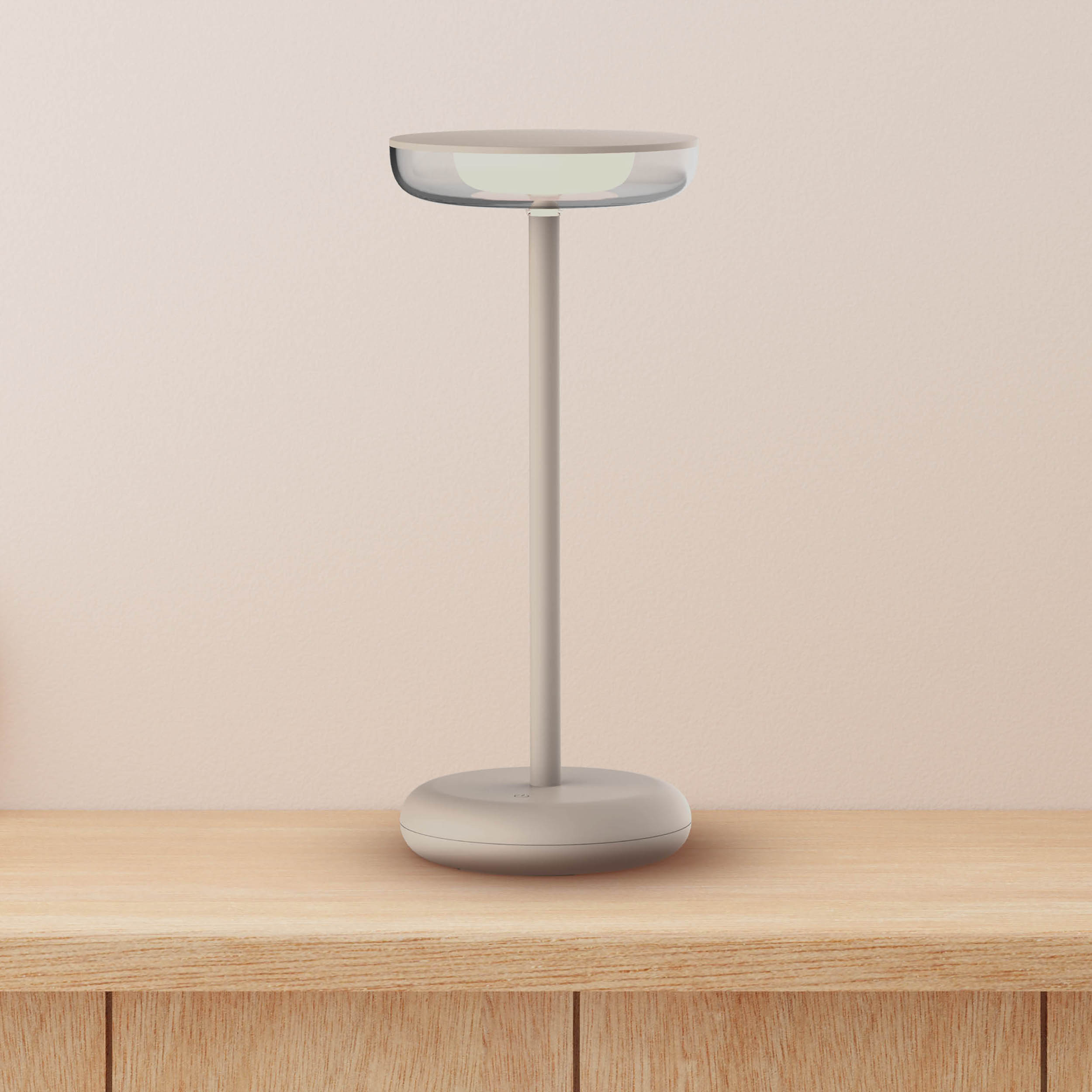 Weiße Lampe mit transparentem Oberteil auf einem Holztisch. Hellbeiger Hintergrund.