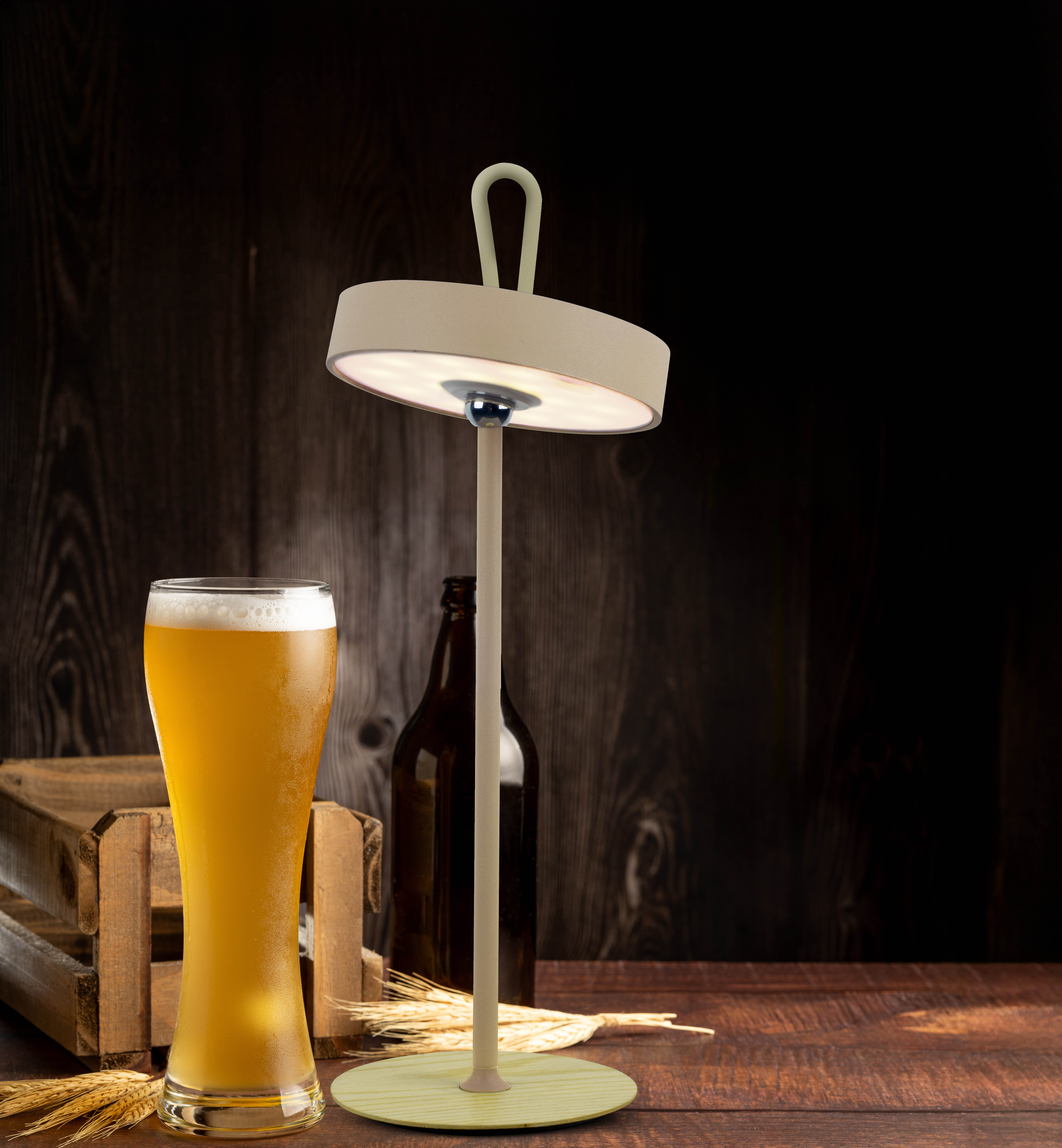 Eine beleuchtete Lampe, Bier und Holzkiste auf einer Holzoberfläche. Dunkler Holzhintergrund.