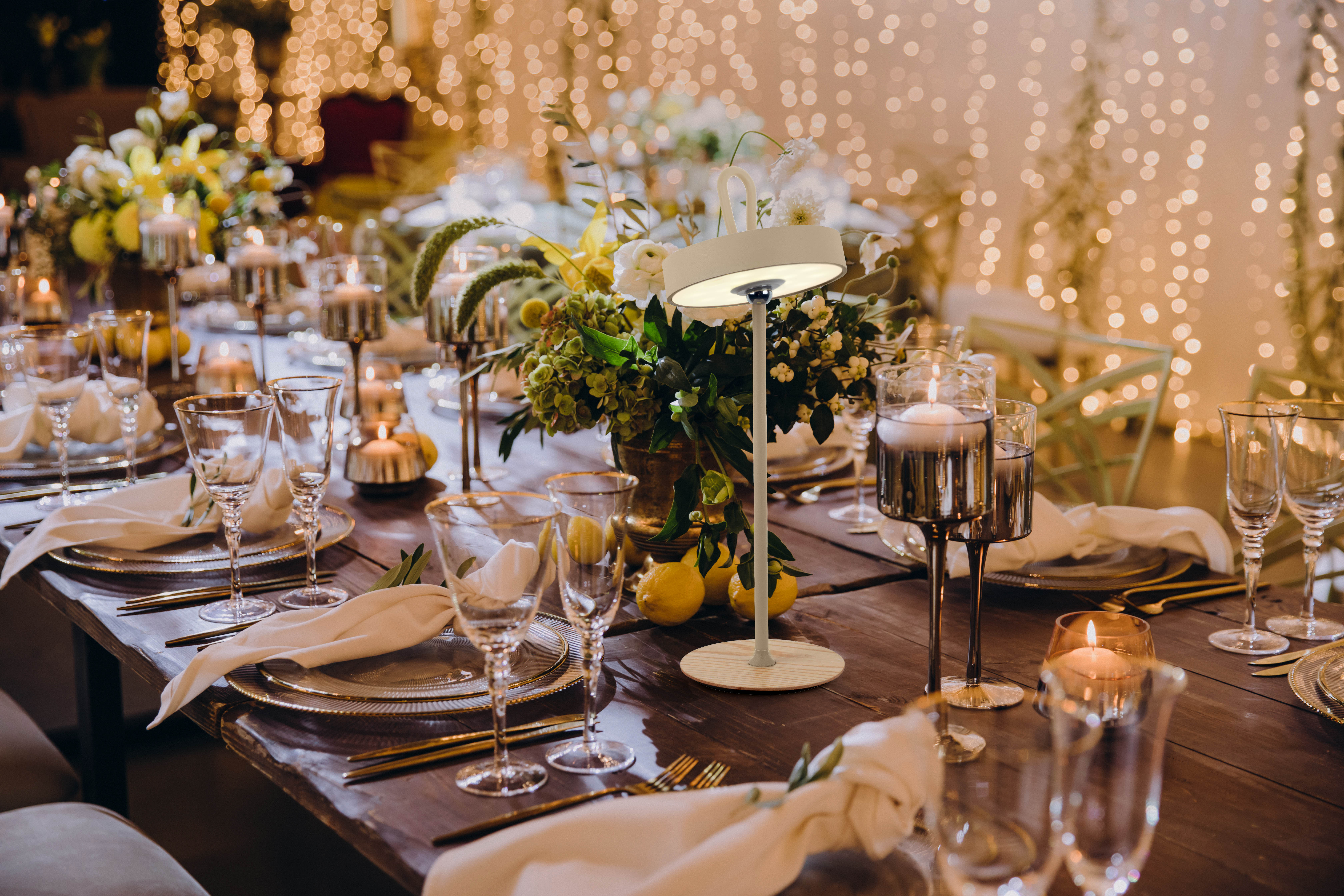 Ein Holztisch, gedeckt für ein Abendessen mit Blumen, Kerzen und Gläsern.
