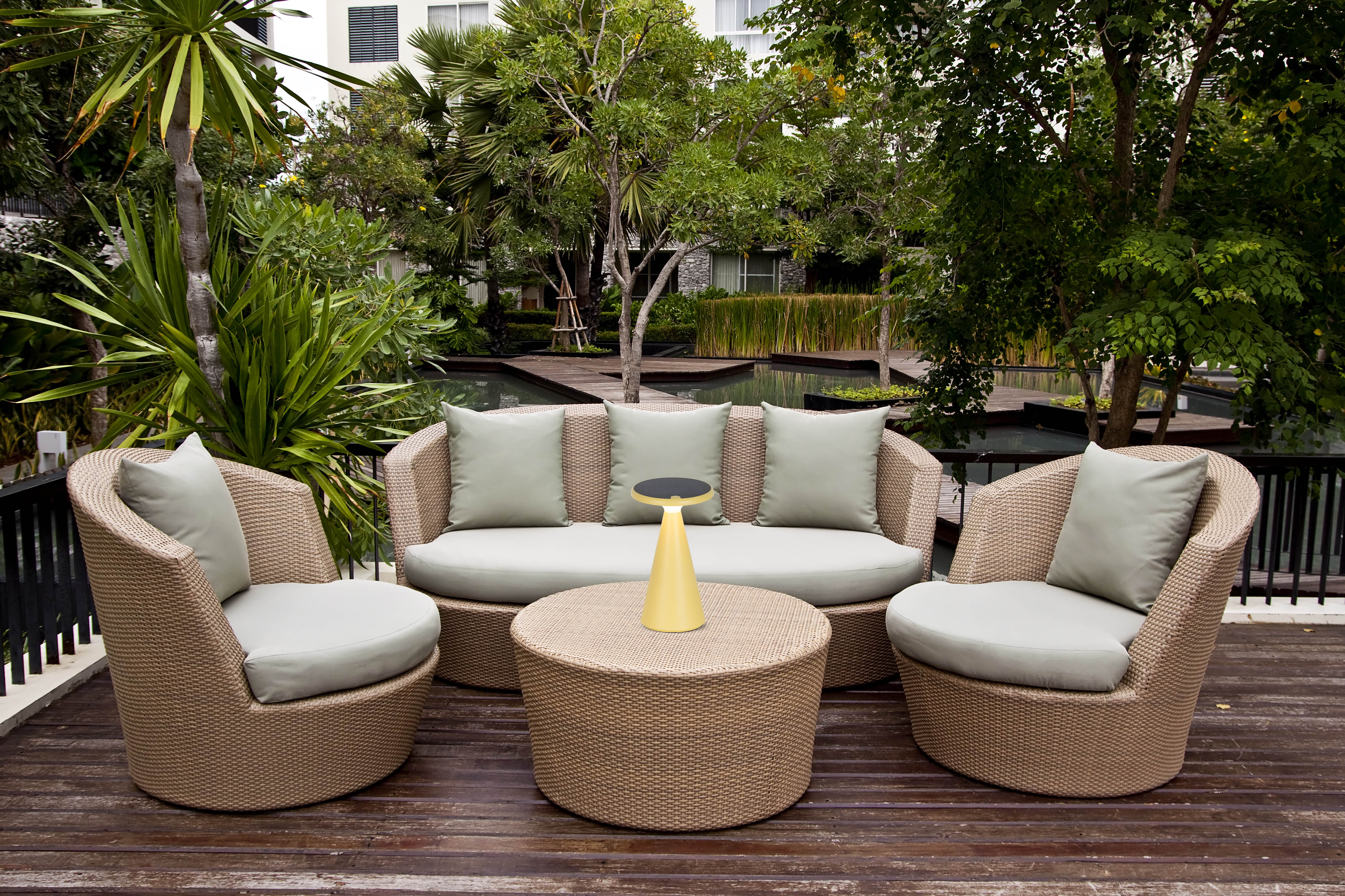 Terrassenmöbel: Korbmöbel-Sofa, zwei Stühle, Couchtisch und Grün im Hintergrund.
