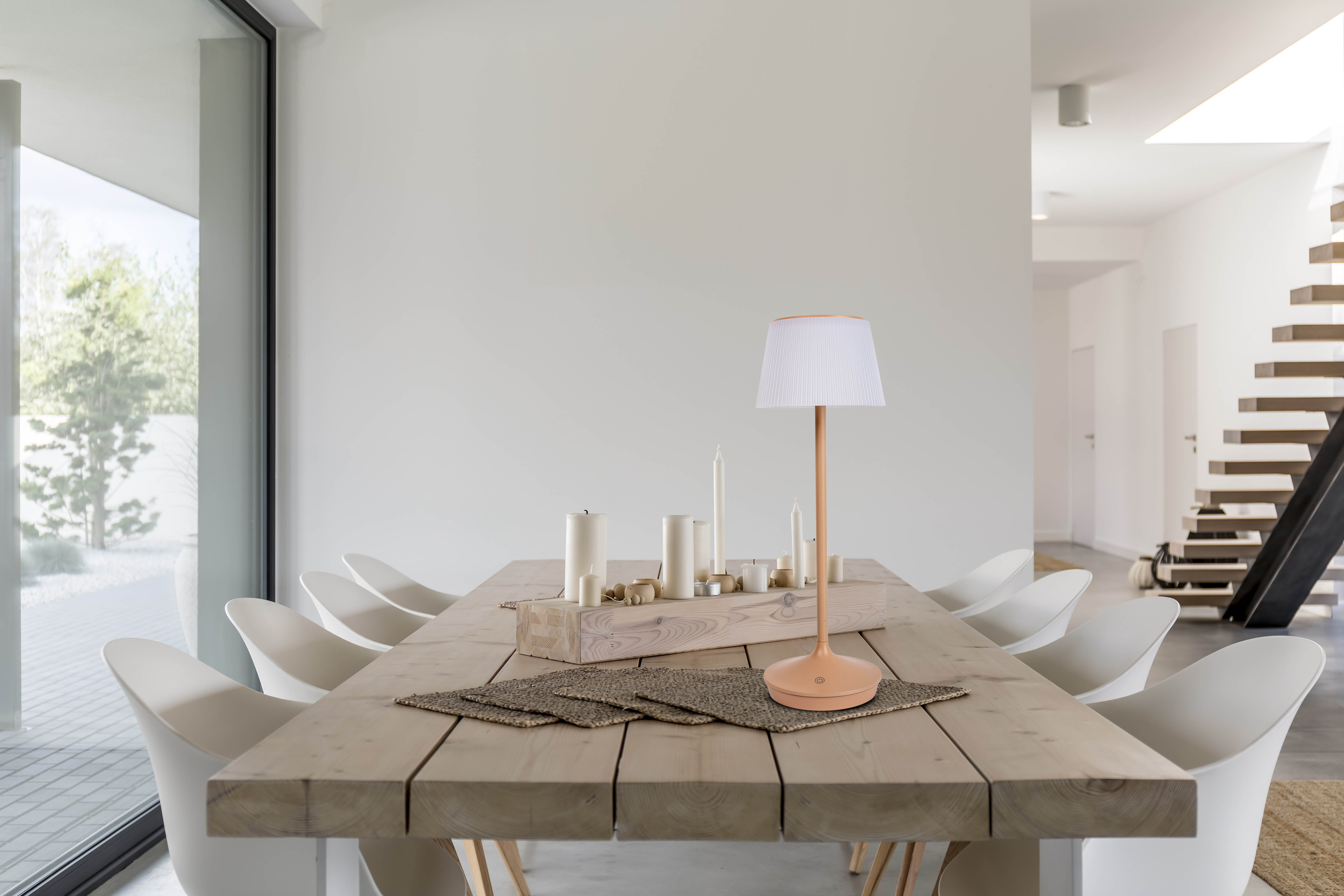 Esstisch mit Lampe, Kerzen und Matten. Ein modernes Interieur mit weißen Wänden.