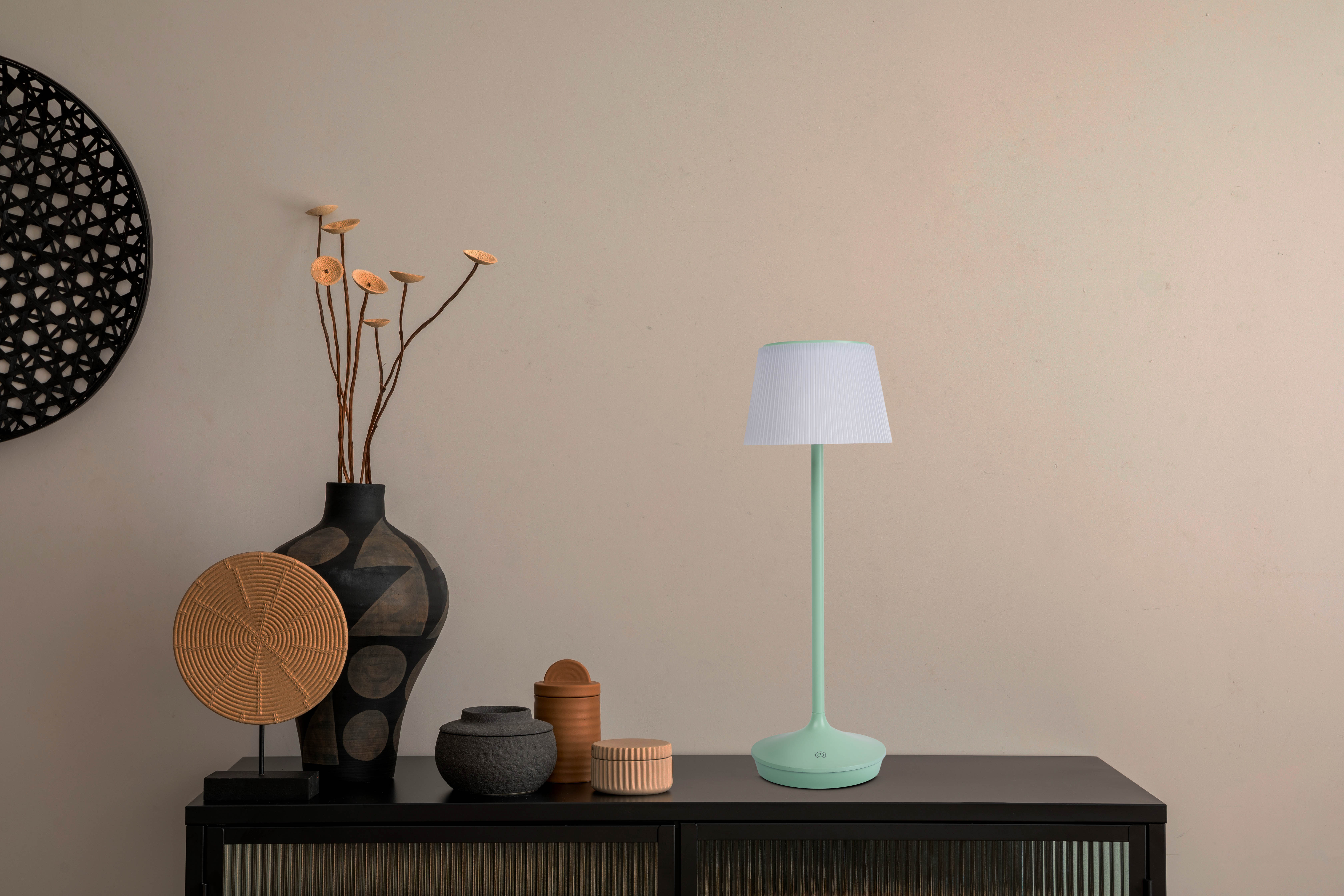 Eine Lampe auf schwarzer Oberfläche mit Deko und beiger Wand.