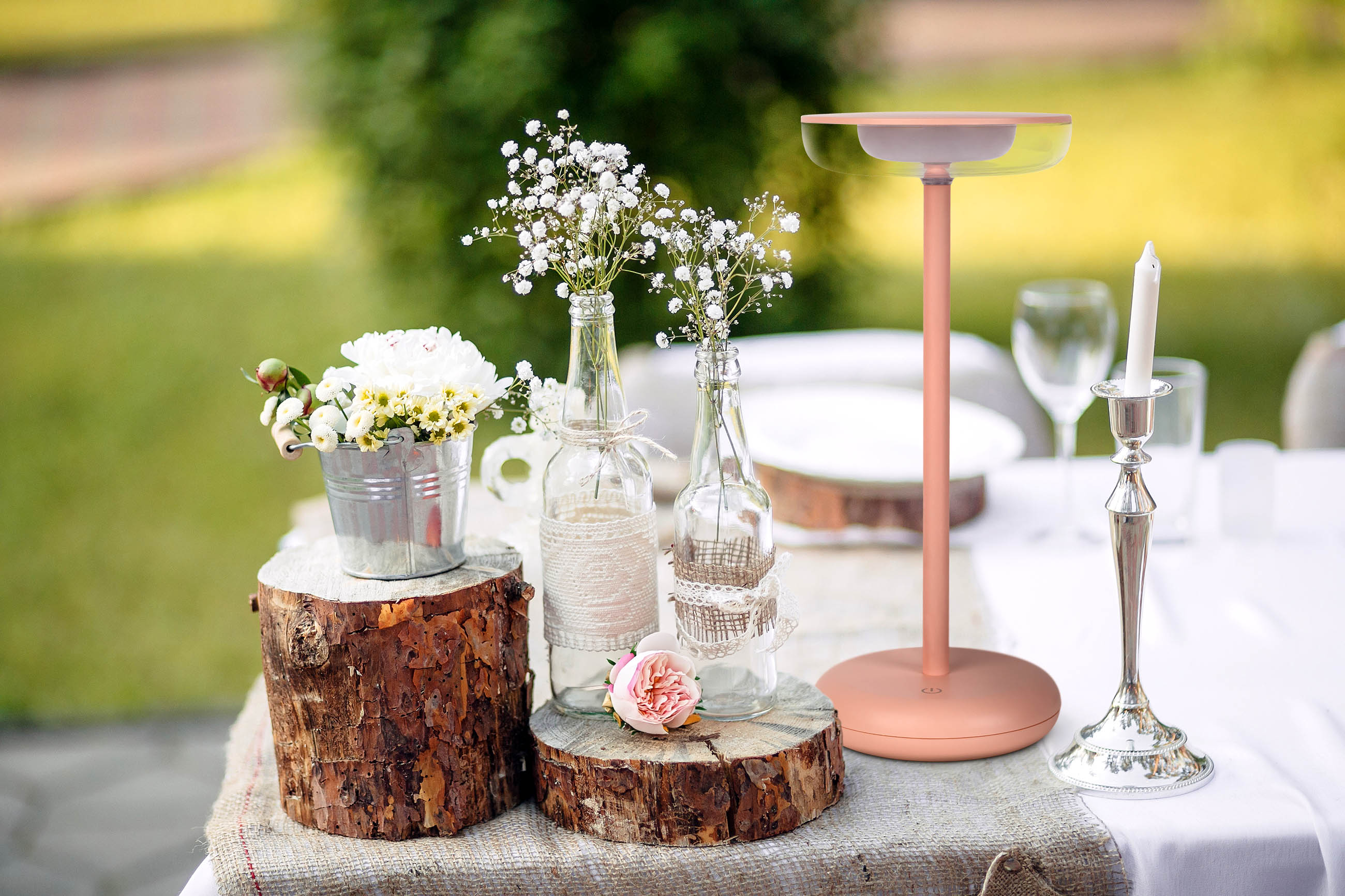 Ein dekorierter Tisch mit Blumen, einem Ständer und einem Kerzenhalter, alles für eine Outdoor-Veranstaltung.
