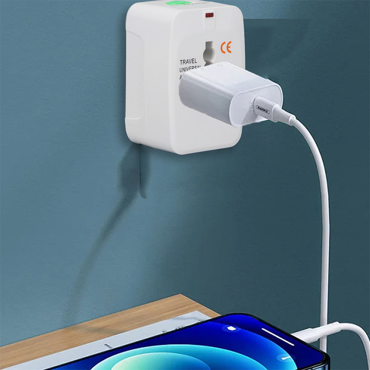 Ein weißer Reiseadapter, der an einer Wand angeschlossen ist. Ein Telefon wird auf einem Holztisch geladen. Blauer Wandhintergrund.