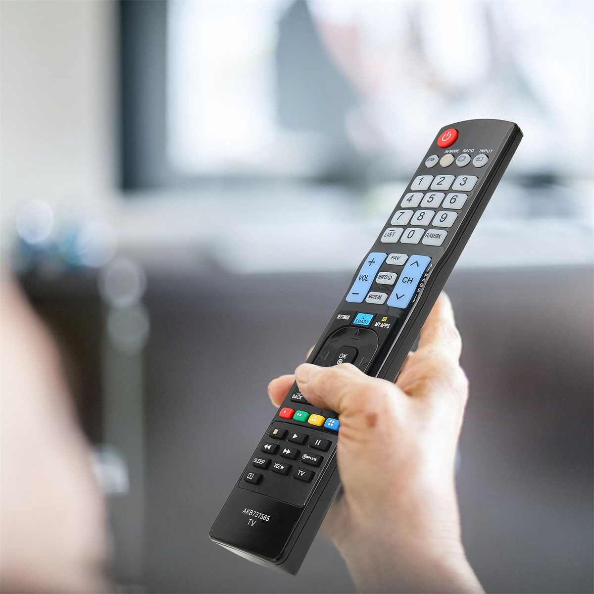 Hand hält eine schwarze TV-Fernbedienung mit verschiedenen Tasten.