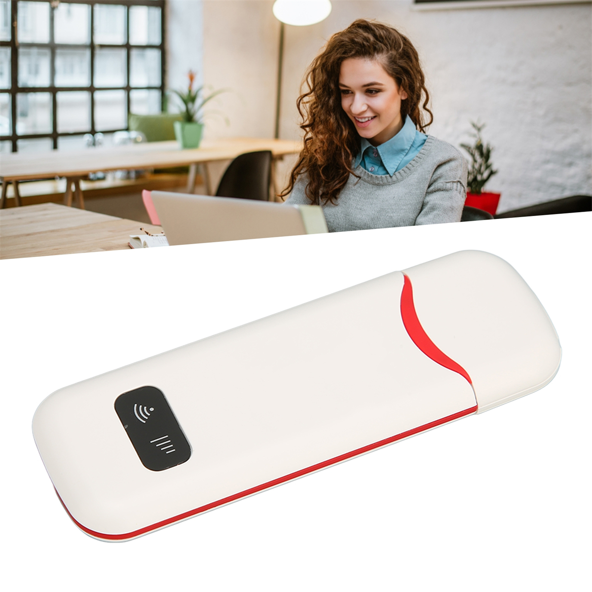 Ein weißes und rotes tragbares Modem, im Hintergrund arbeitet eine Frau an einem Laptop.
