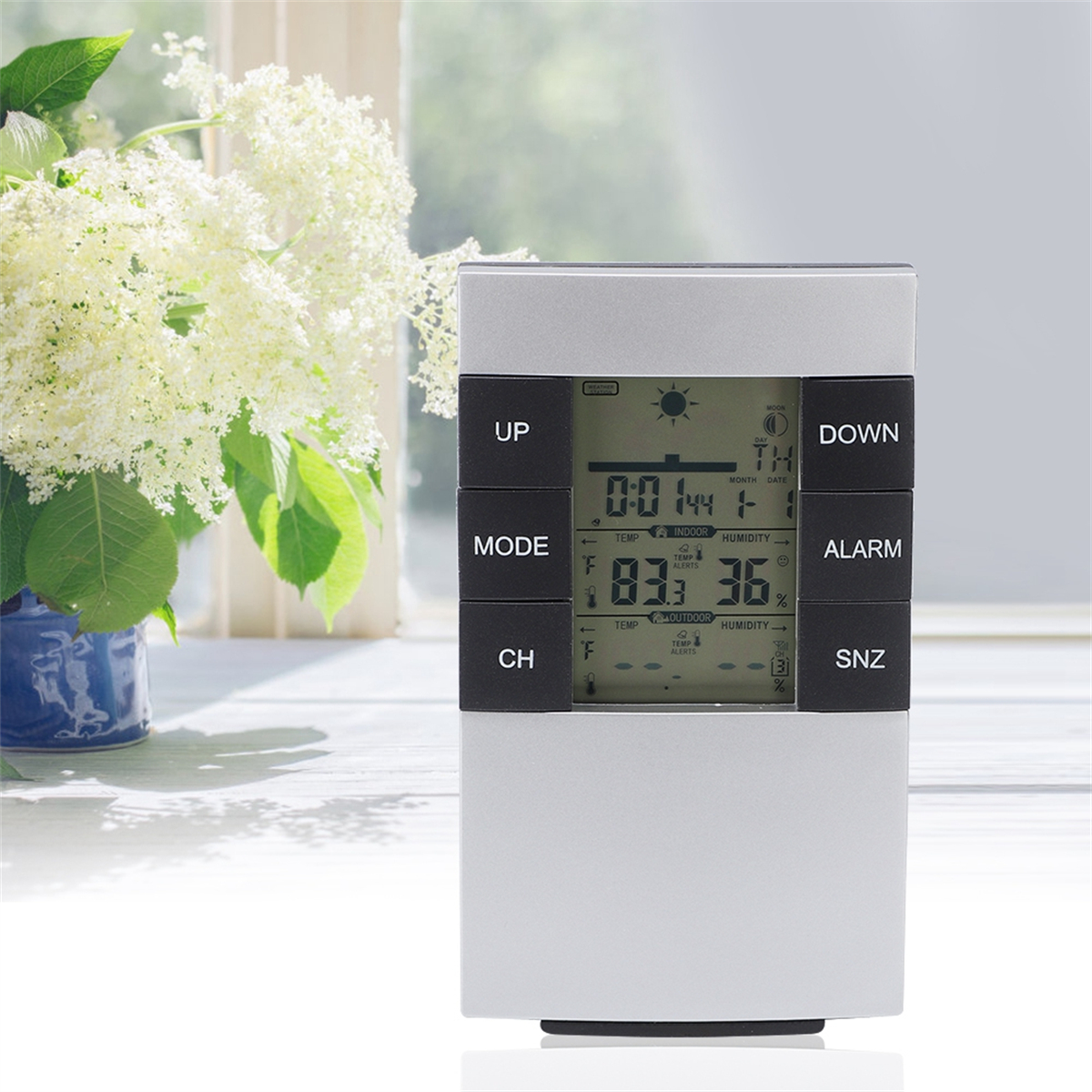 Eine digitale Wetterstation mit Knöpfen, die Zeit, Temperatur, Luftfeuchtigkeit und Datum anzeigt.
