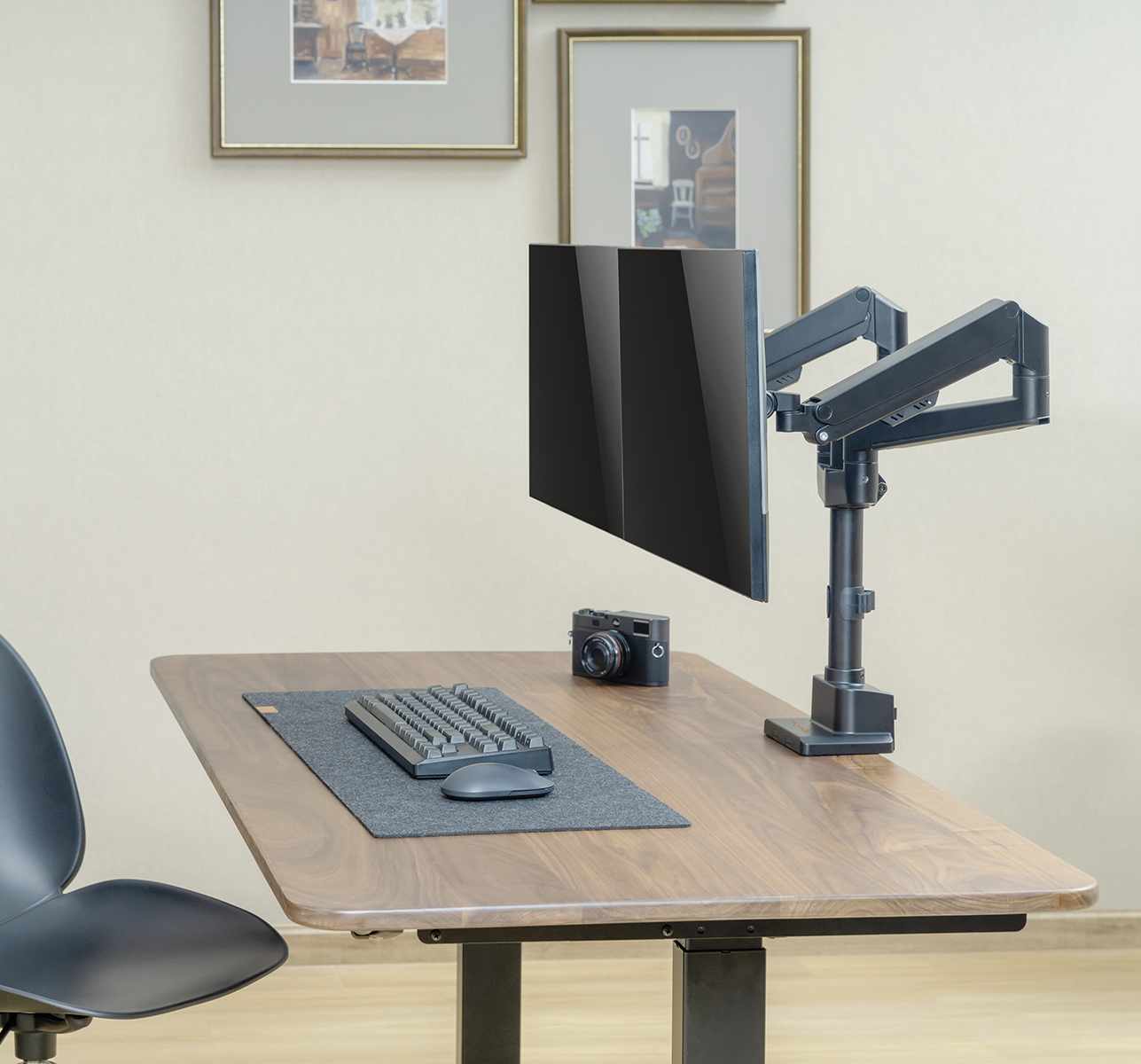 Ein Schreibtisch mit Monitor, Tastatur, Kamera und Bildern.