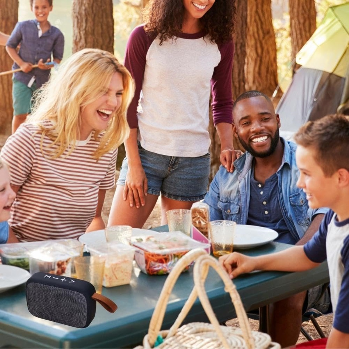 Famiglia al picnic. Persone sorridenti. Un altoparlante bluetooth sul tavolo.