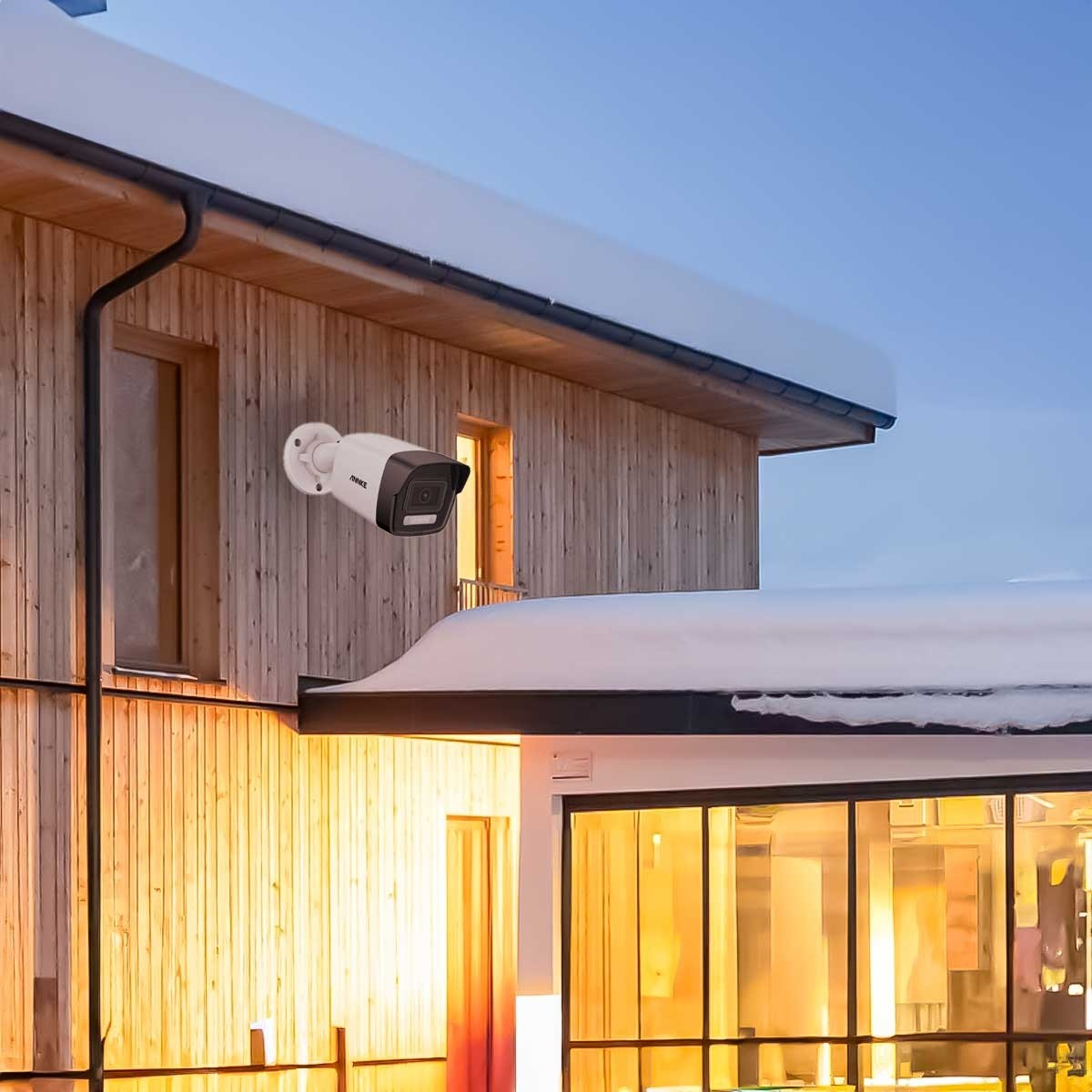 Eine Überwachungskamera an einem Holzhaus montiert. Das Haus hat Fenster und ein dunkles Dach.