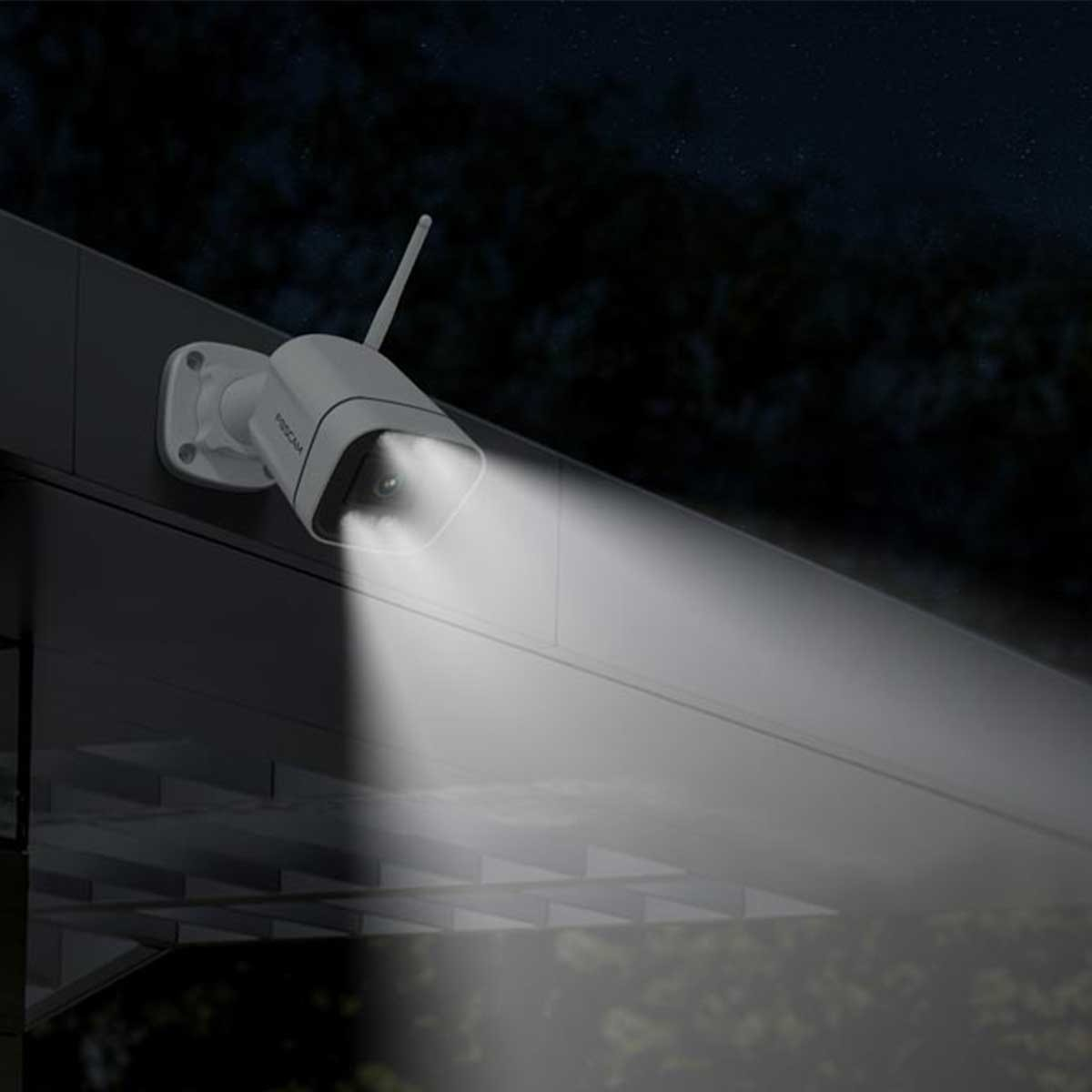 Kamera bezpieczeństwa zamontowana na budynku, świecąca reflektorem w nocy.