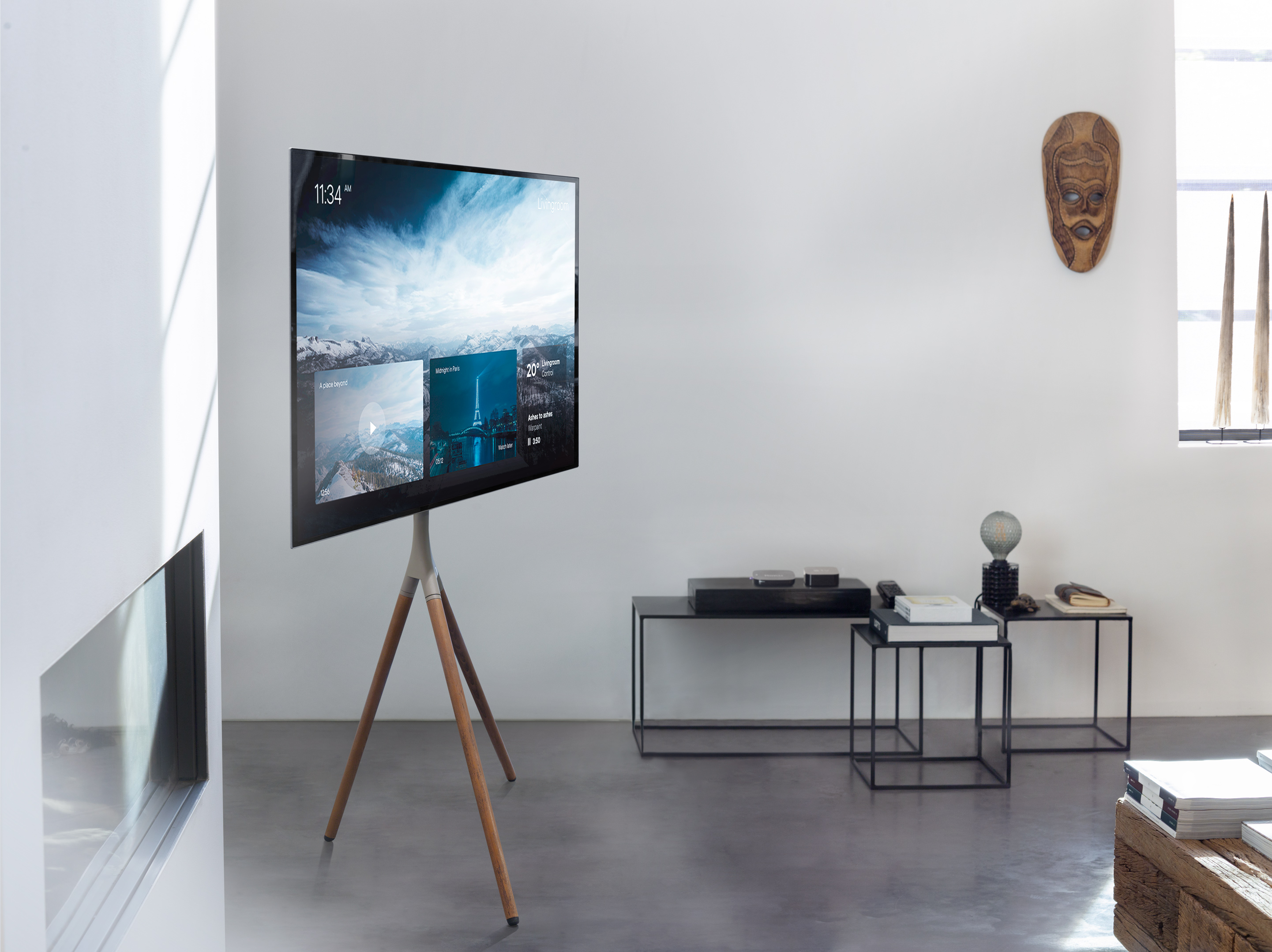 TV moderne sur trépied en bois. Mur blanc, table noire, décor et sculpture sur bois. Scène d'intérieur.