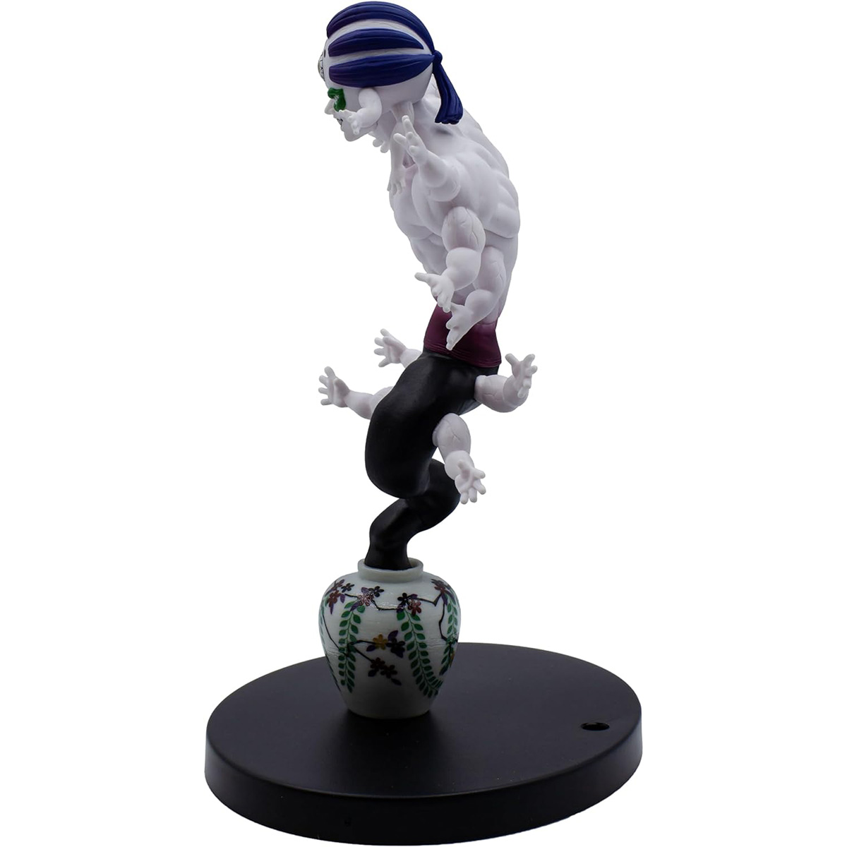 Una figura de una figura retorcida encima de un jarrón, sobre una base redonda. La figura es blanca, negra y tiene una venda verde.